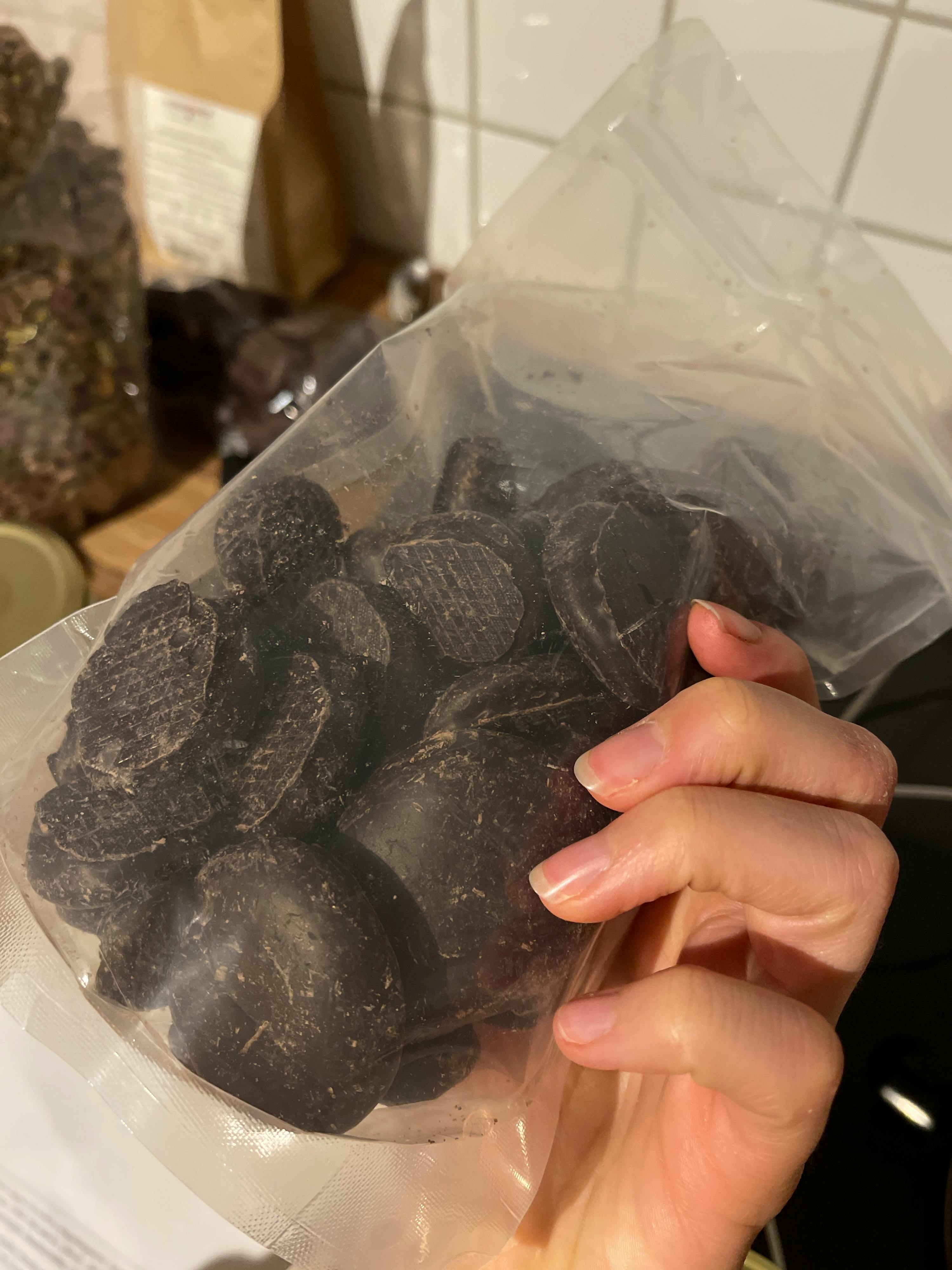 Eine Person hält einen Plastikbeutel mit Schokoladenstücken in der Hand