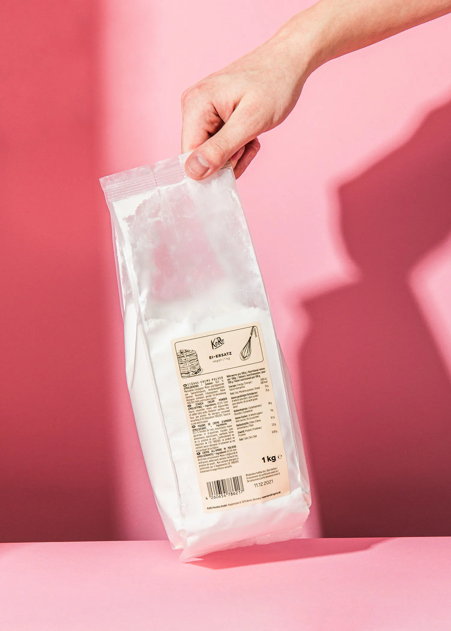 une personne tient un sac de farine blanche sur fond rose