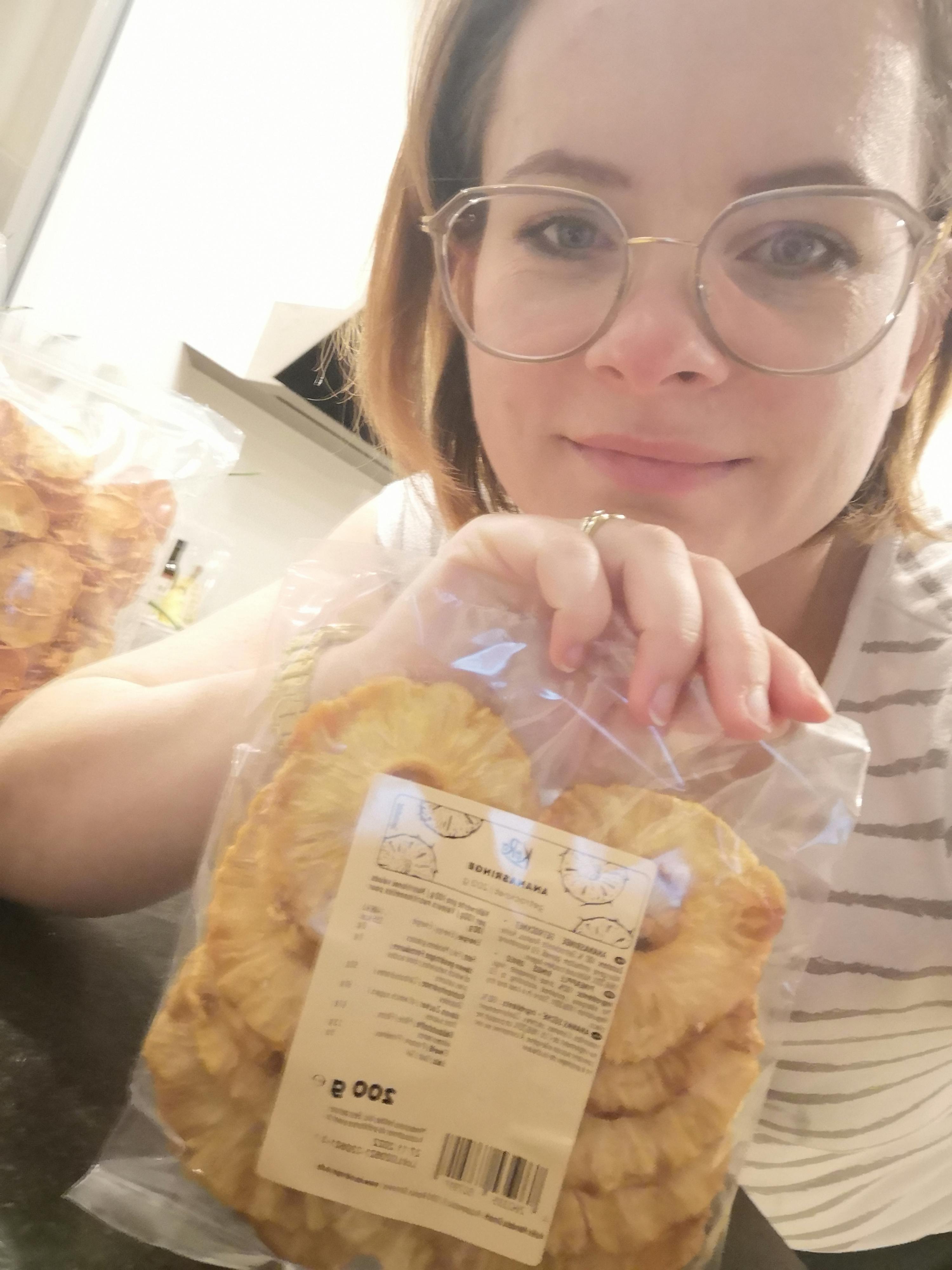 eine frau mit brille hält einen plastikbeutel mit ananasscheiben