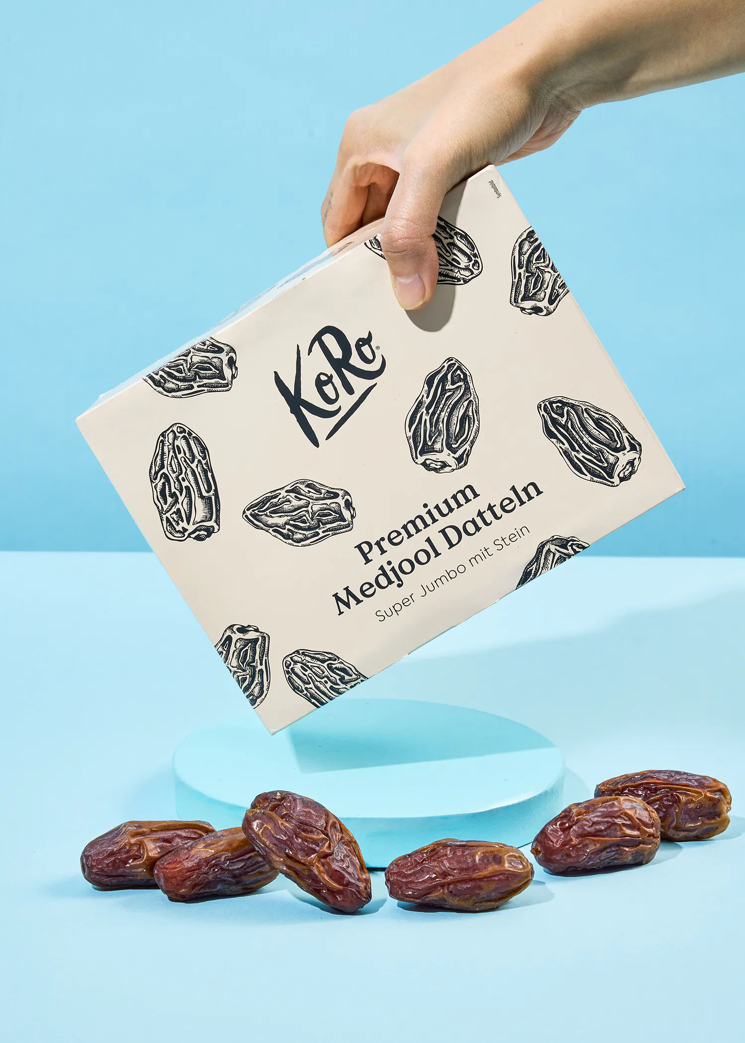 eine hand hält eine verpackung mit premium medjool datteln