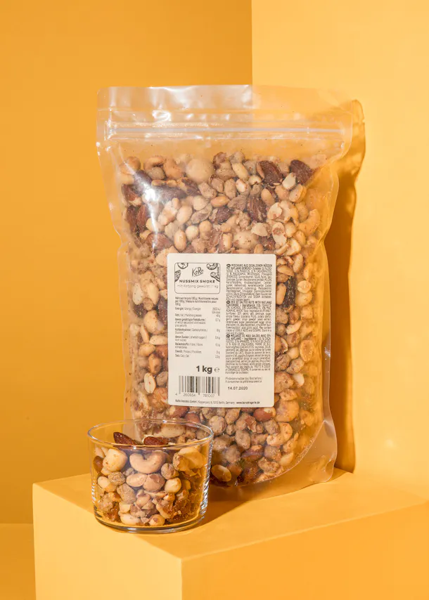 eine Tüte Erdnüsse steht neben einem Glas mit Erdnüssen