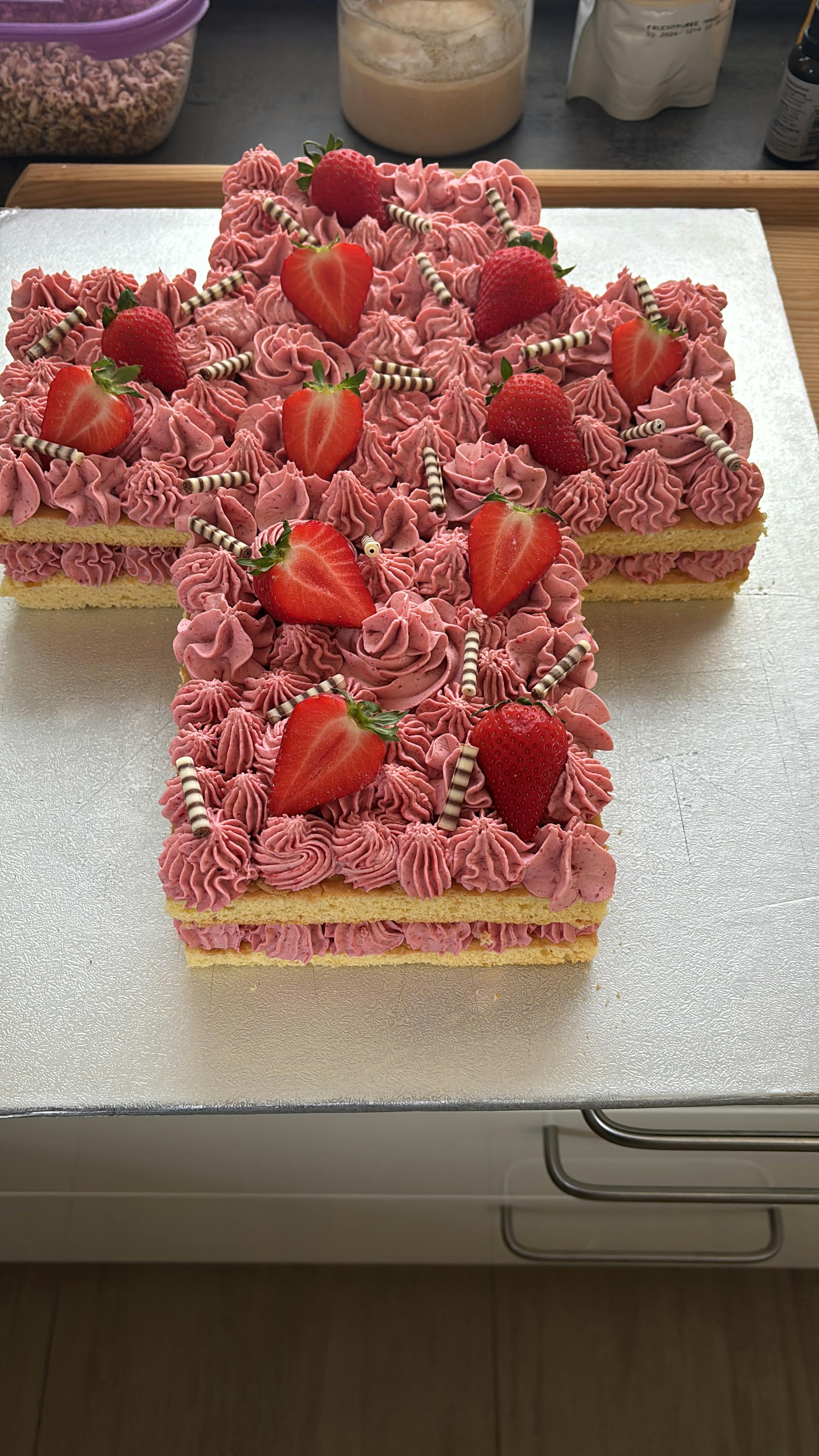 a cake with strawberries and pink frosting in the shape of the letter h