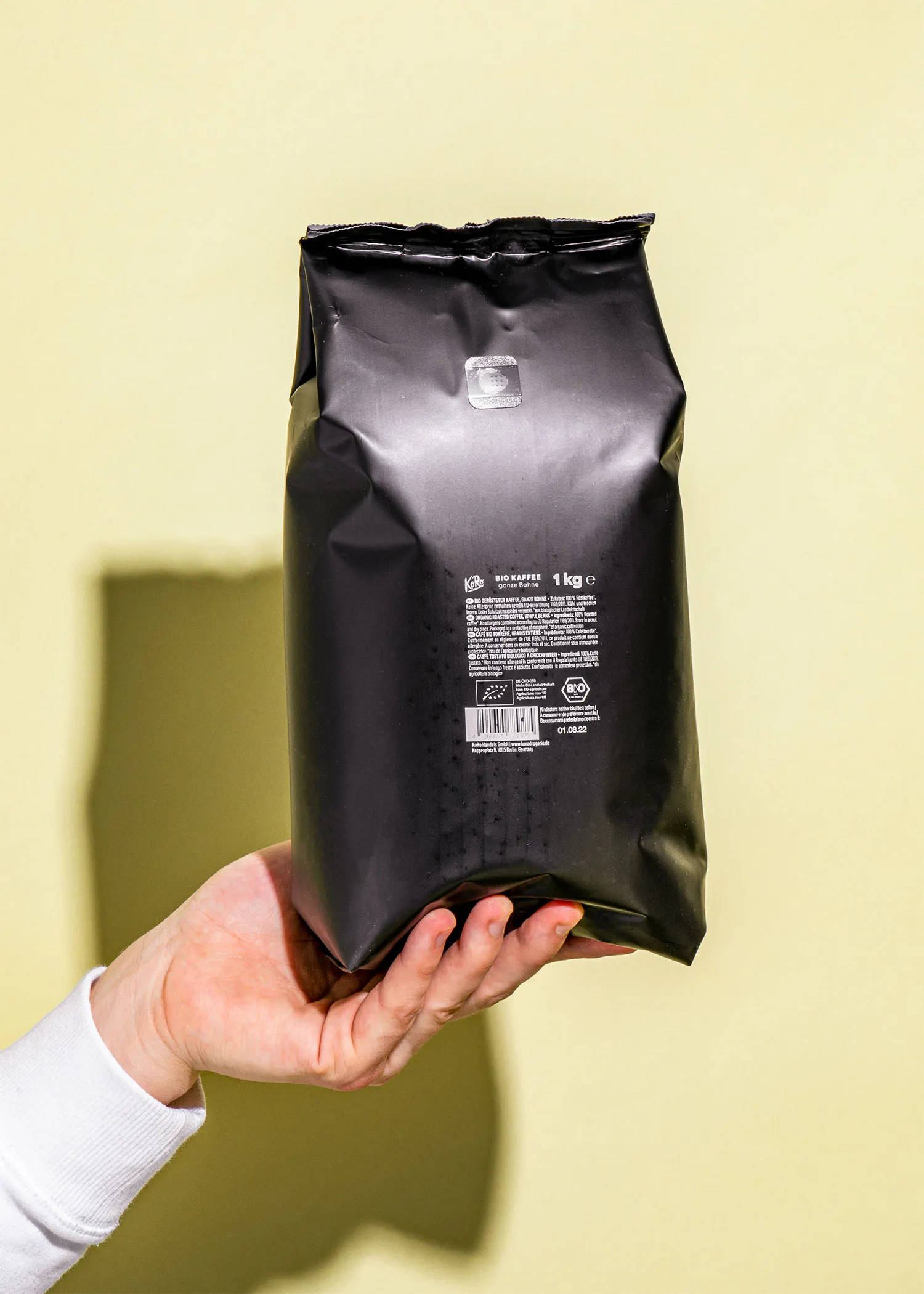 une personne tient un sac en plastique noir de 1 kg