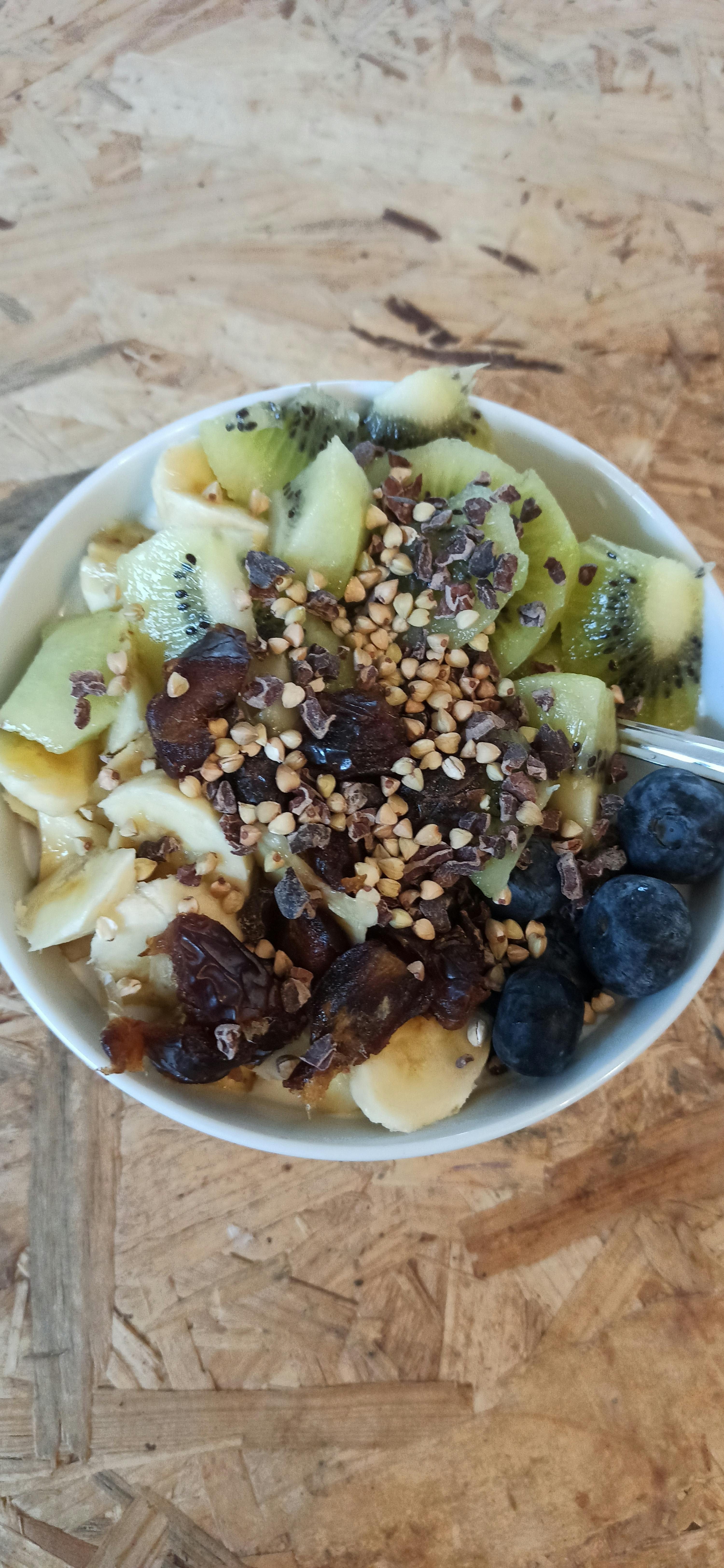a bowl of fruit and nuts with a fork in it