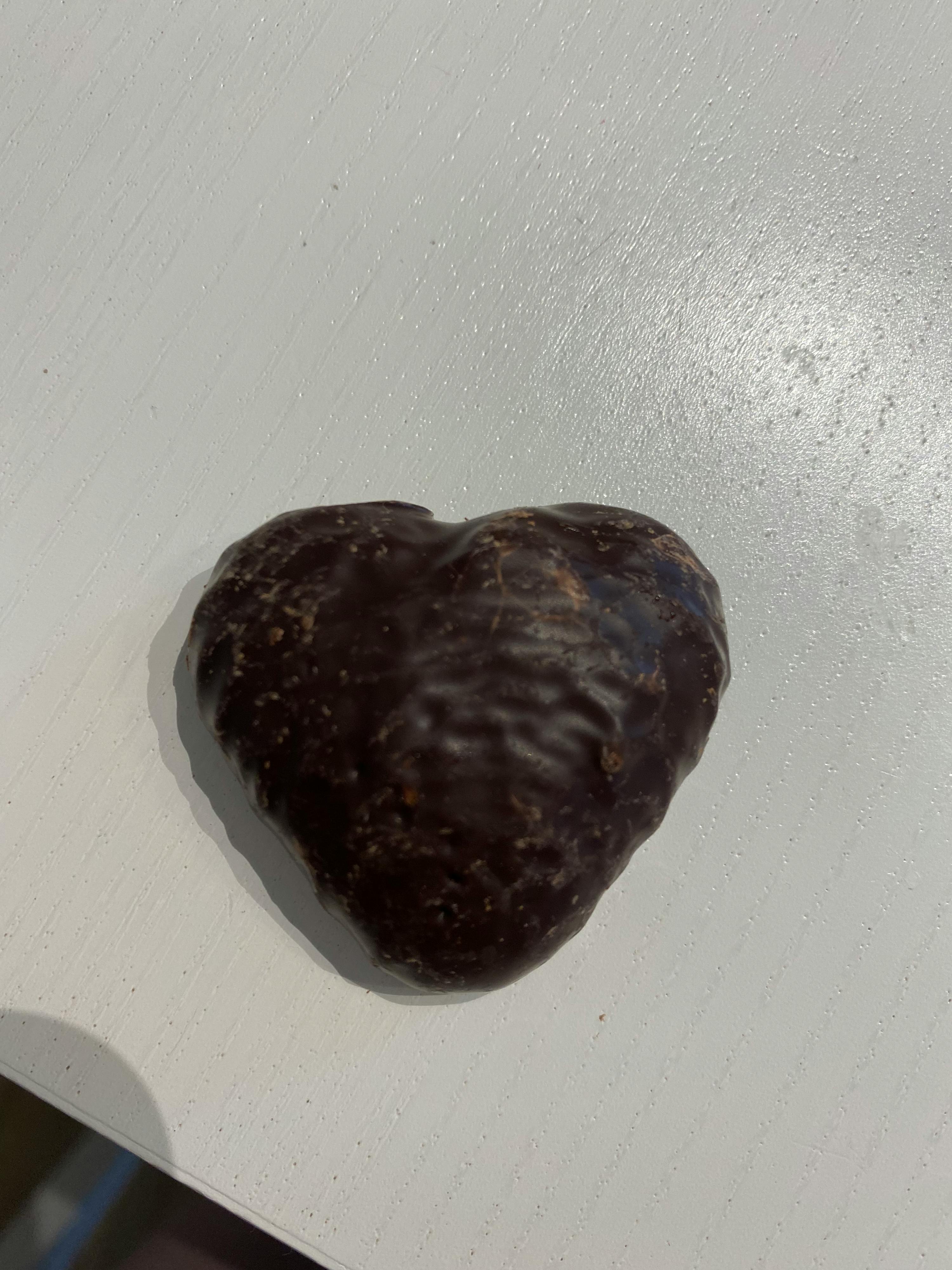 a heart shaped chocolate candy is sitting on a white surface