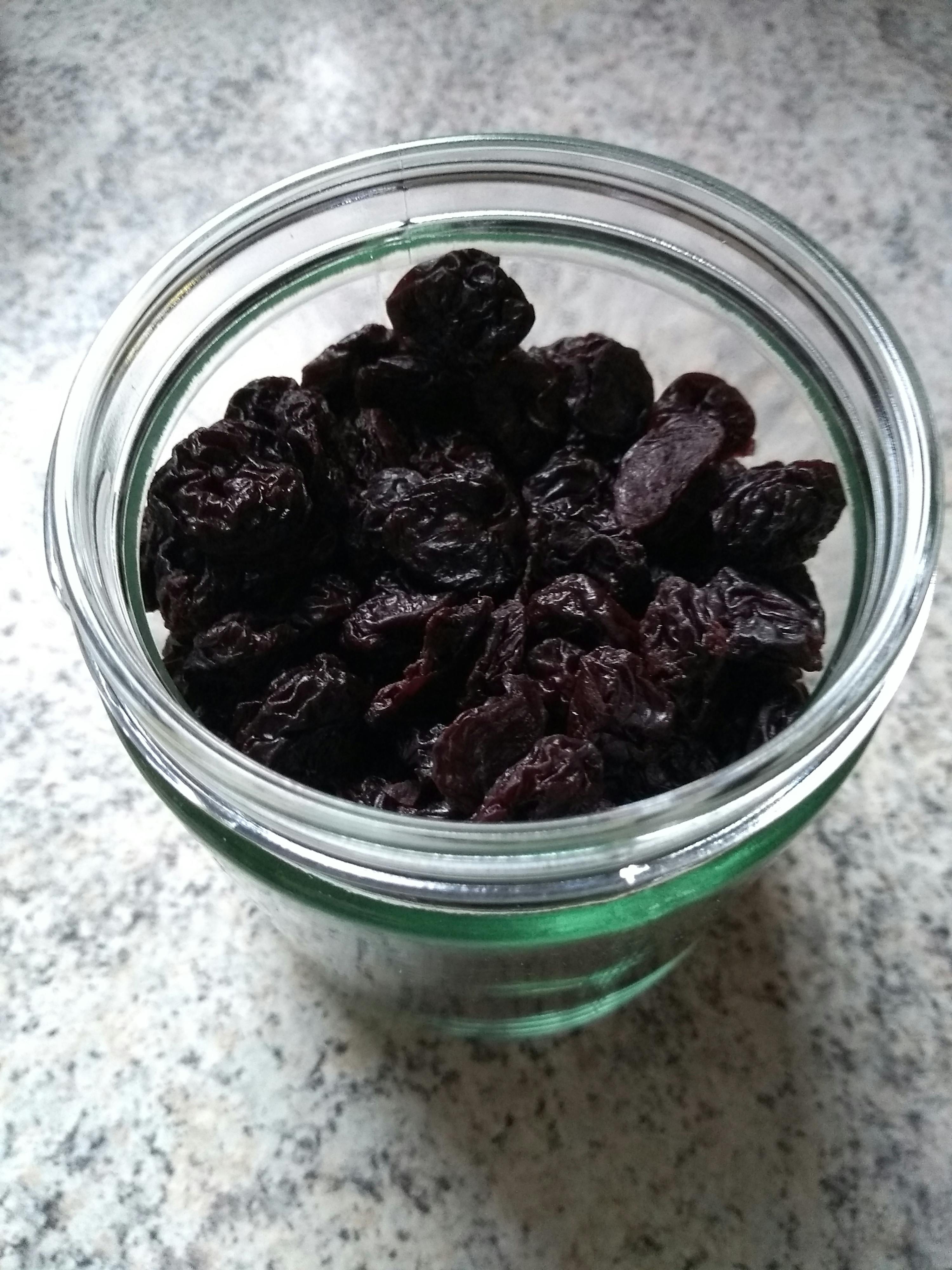 un bol en verre rempli de raisins noirs sur une table