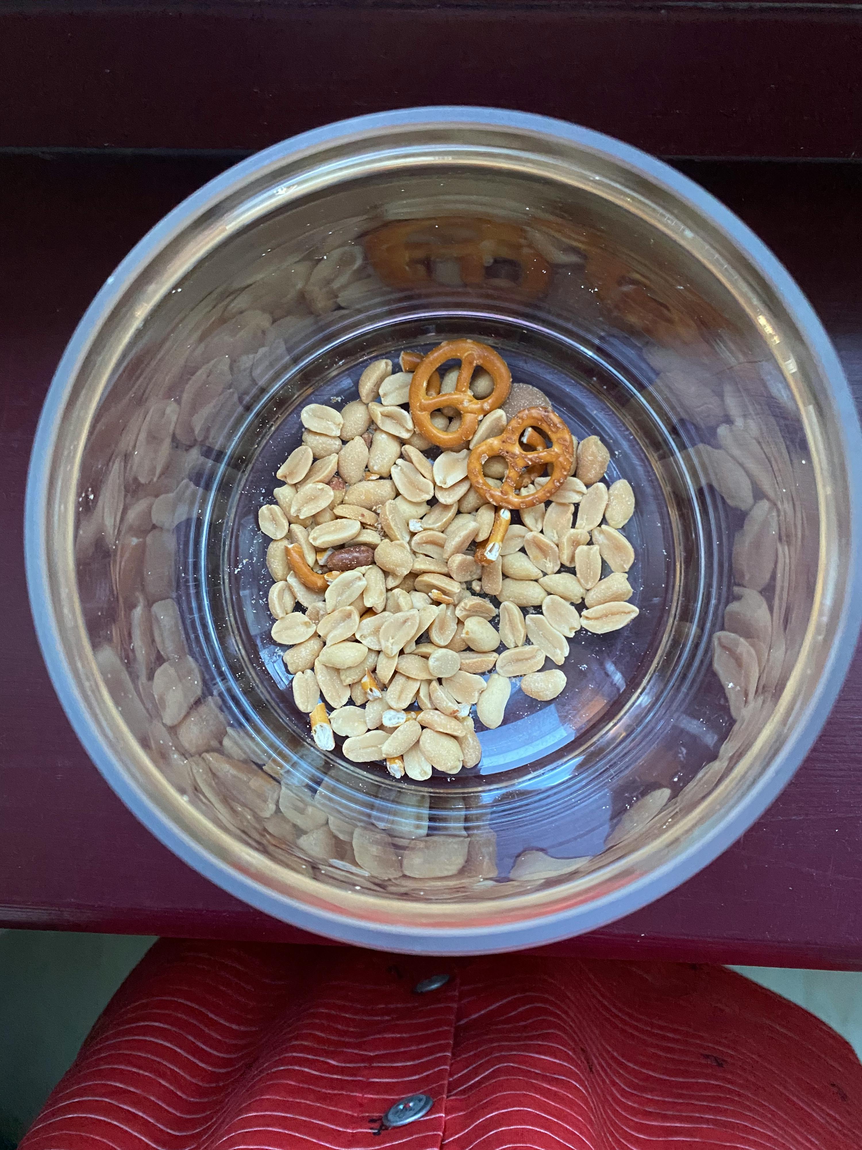 un bol en plastique rempli de cacahuètes et de bretzels