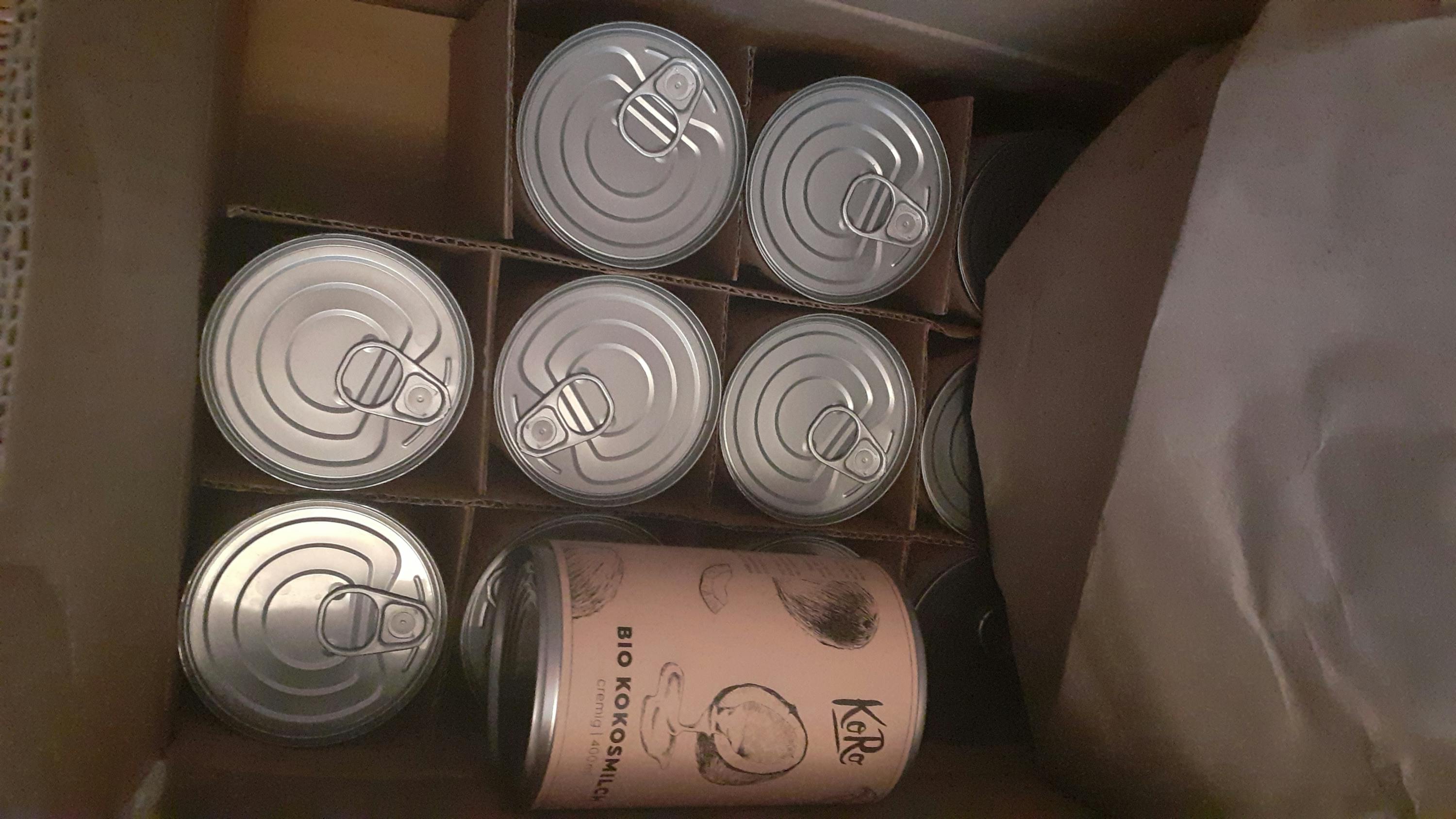 several cans of bio kokosmilch are in a cardboard box
