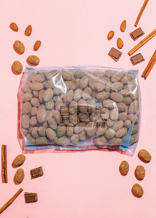 a bag of chocolate covered almonds is on a pink surface