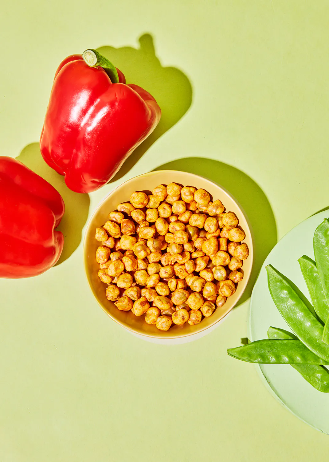 eine Schüssel mit gerösteten Kichererbsen neben einer roten Paprika