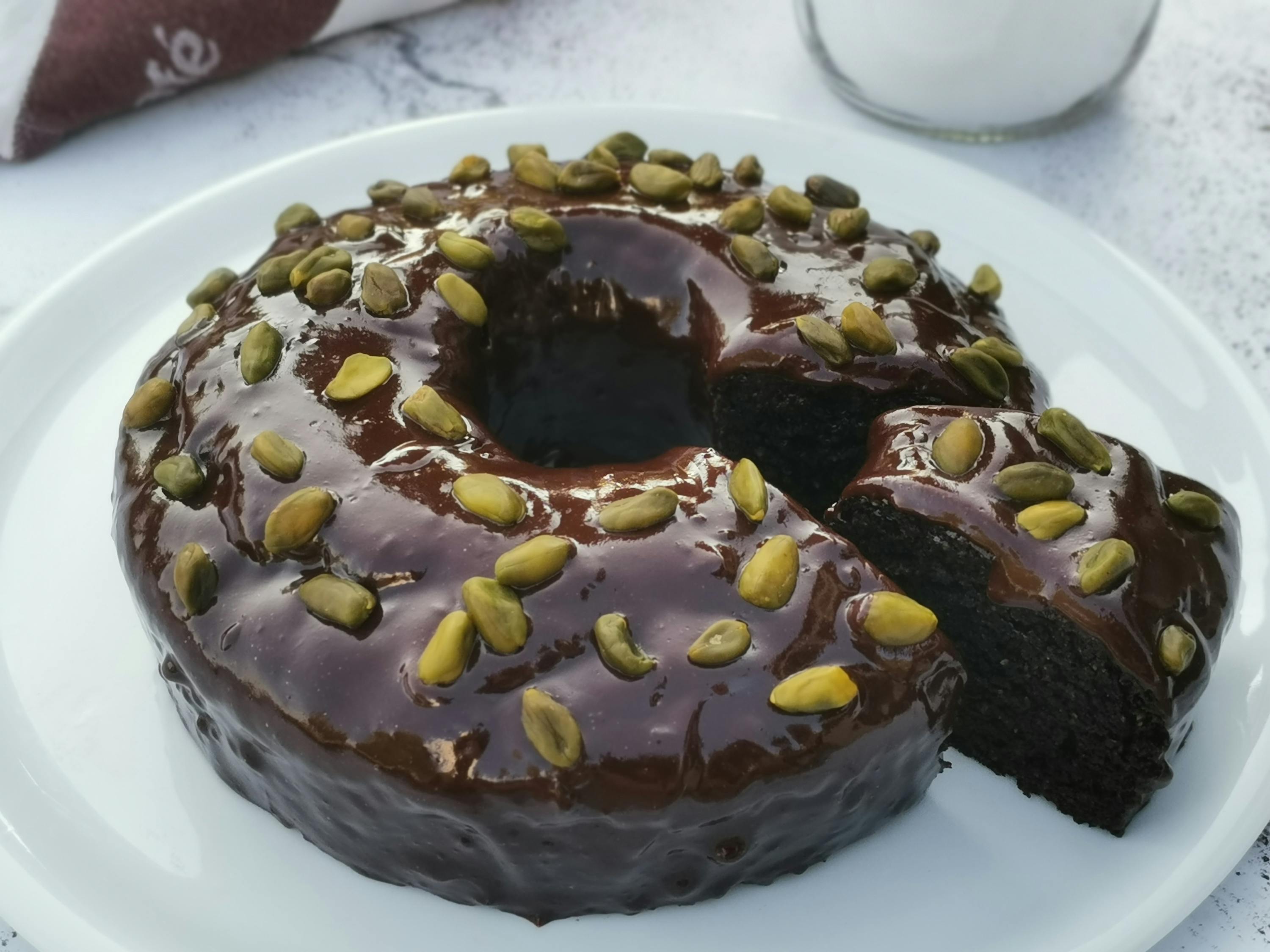 a chocolate cake with pistachios on top is on a white plate