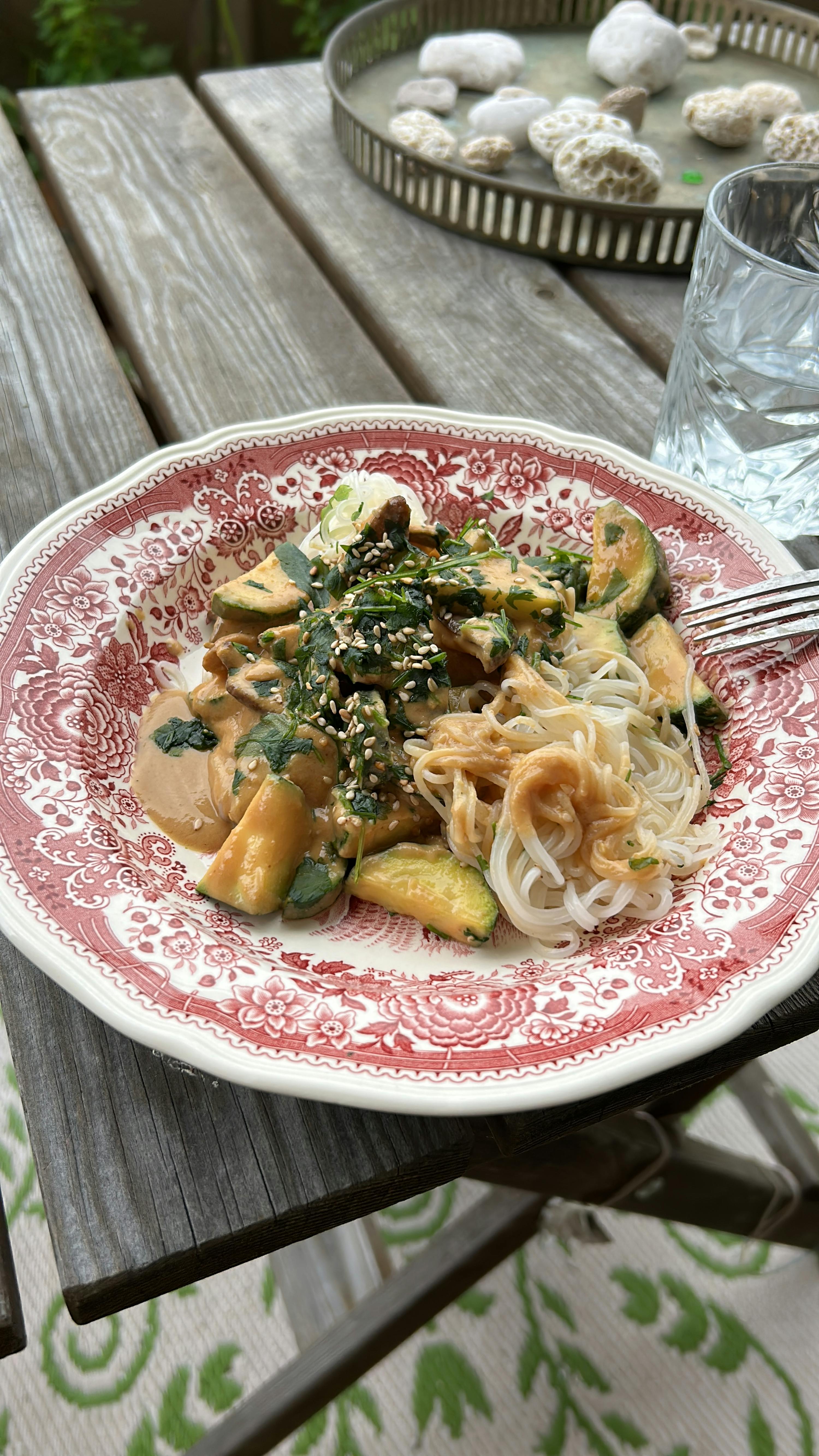 a plate of food with noodles and vegetables on a table