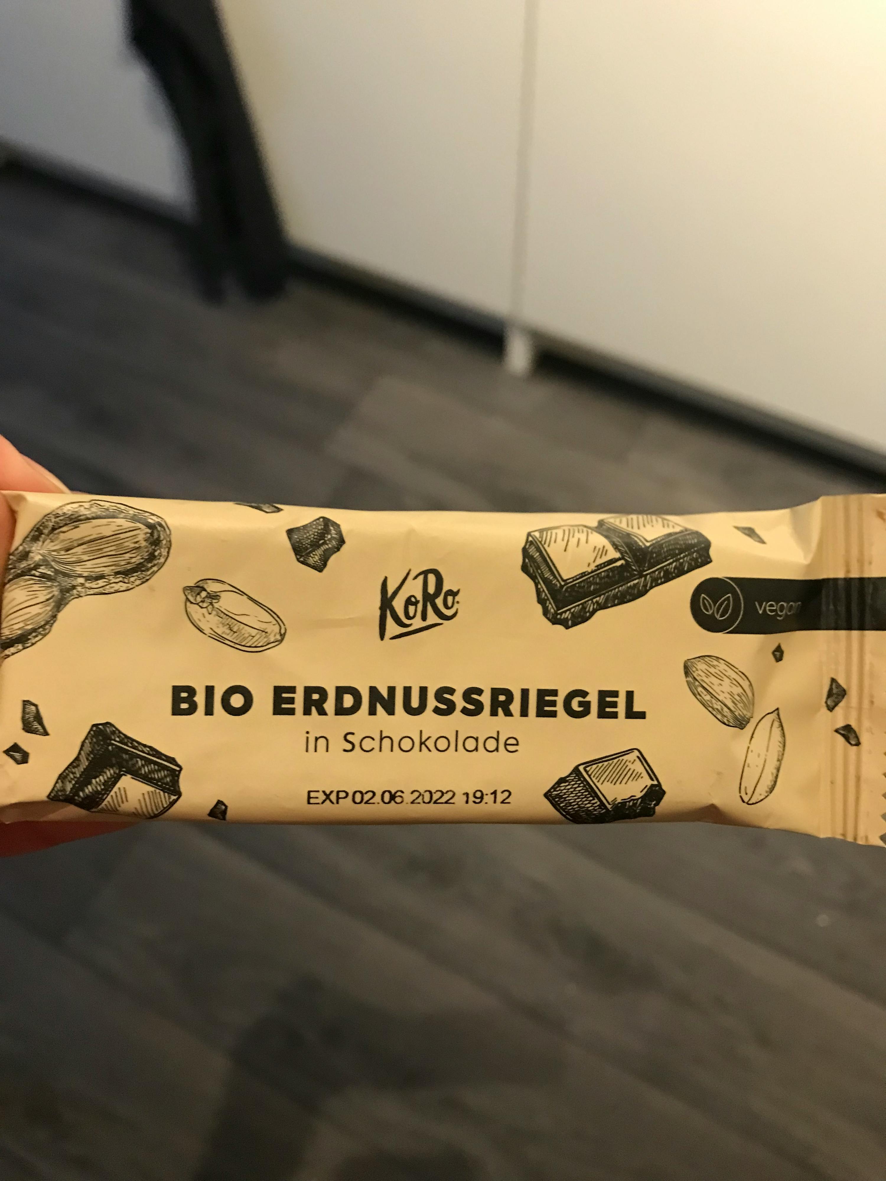 Eine Person hält einen Bio Erdnussriegel in Schokolade