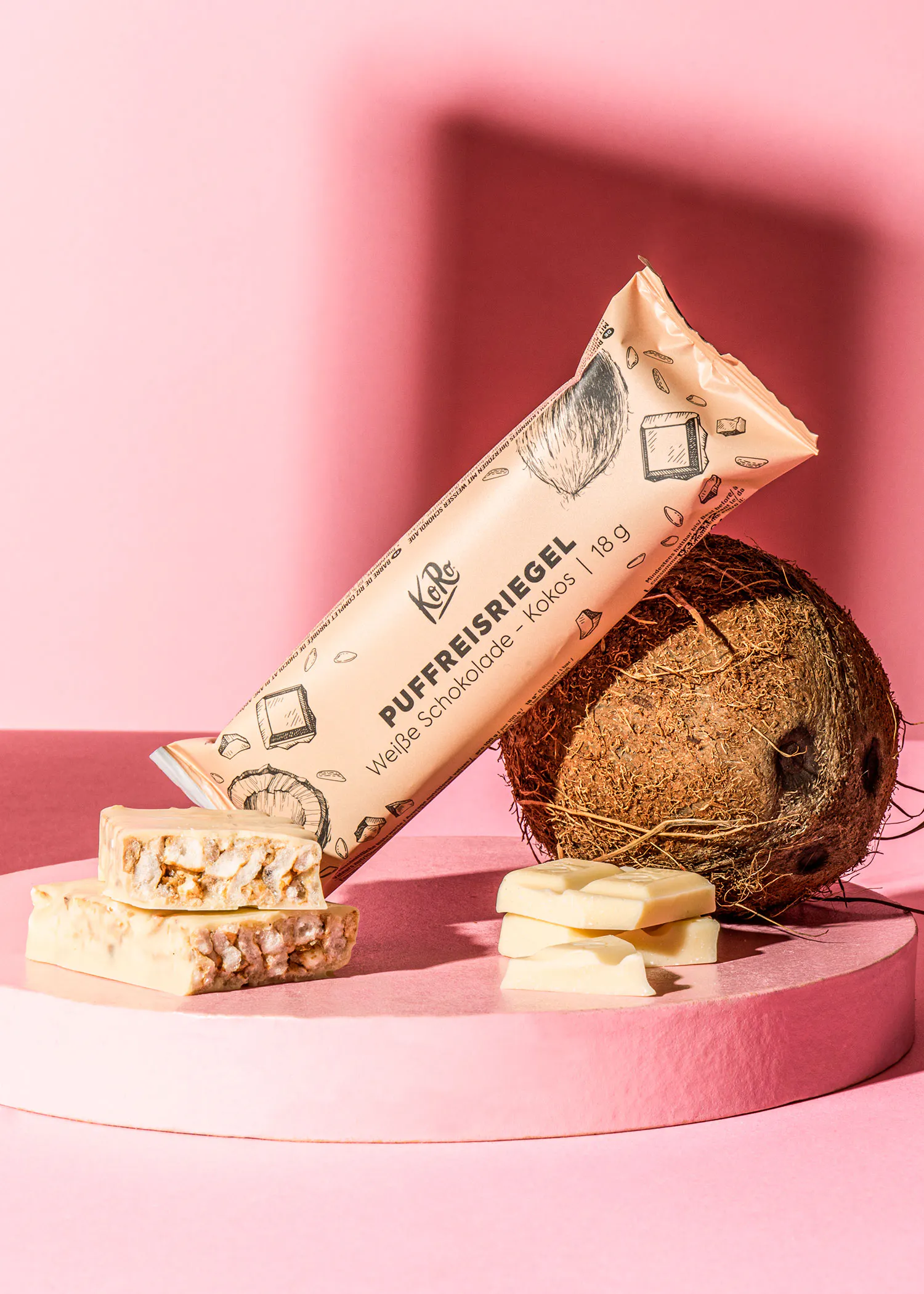 une barre de chocolat blanc est posée sur une table rose à côté d' une noix de coco