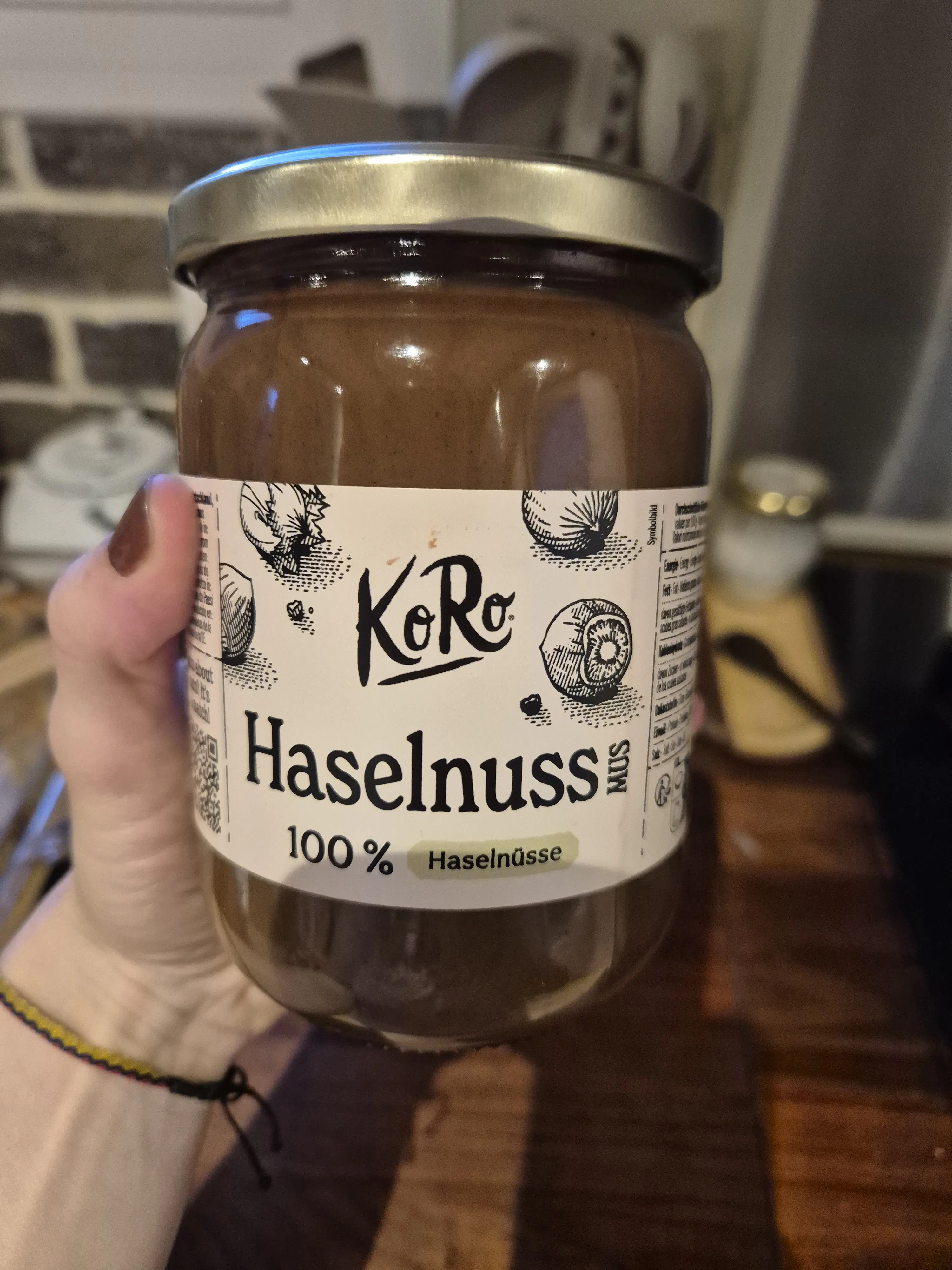 un pot de pâte à tartiner aux noisettes koro 100% noisettes est tenu par une main.