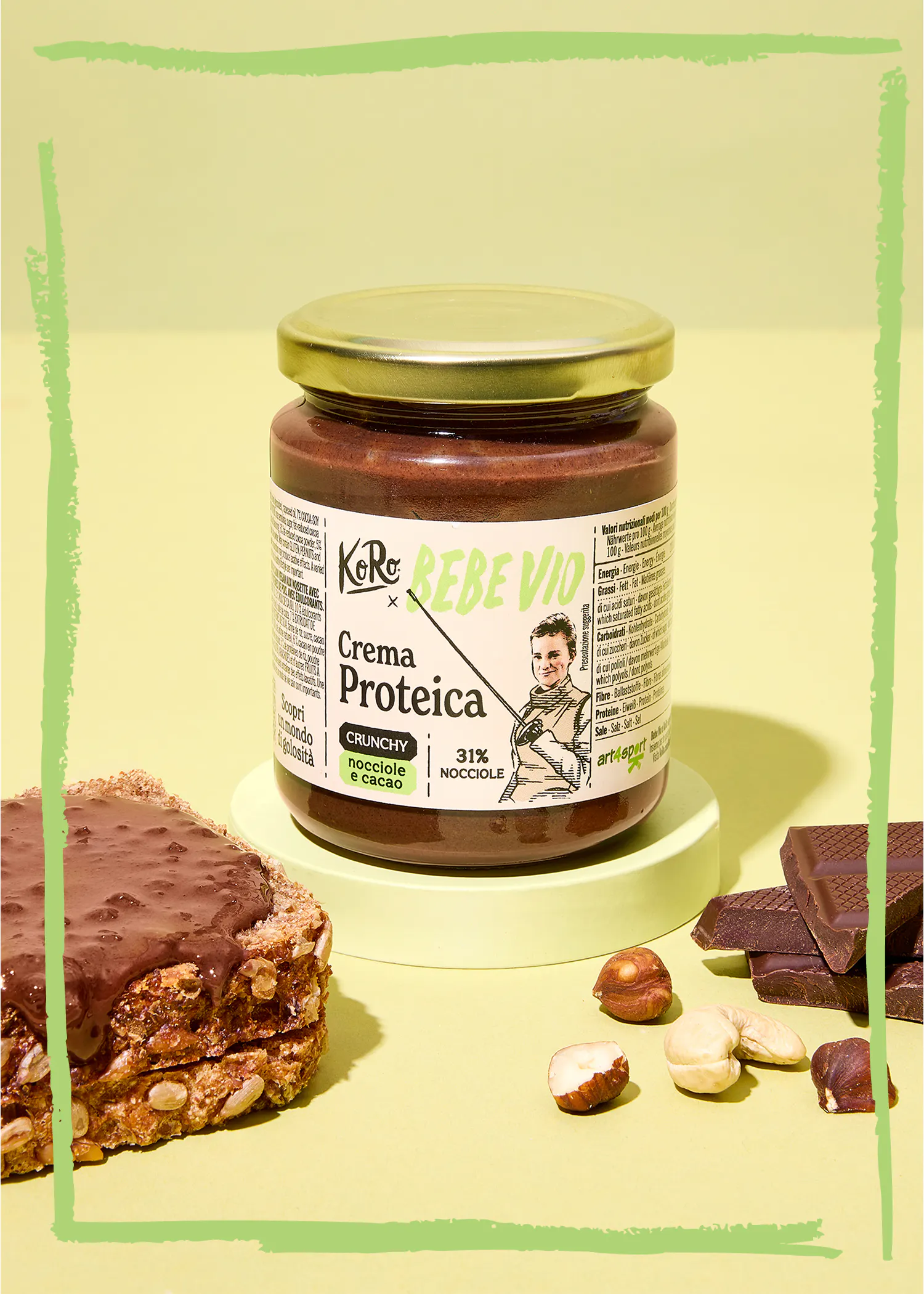 un barattolo di crema proteica koro rebe vio crunchy nocciole e cacao su un piedistallo verde, affiancato da una fetta di pane spalmata, nocciole, anacardi e pezzi di cioccolato.