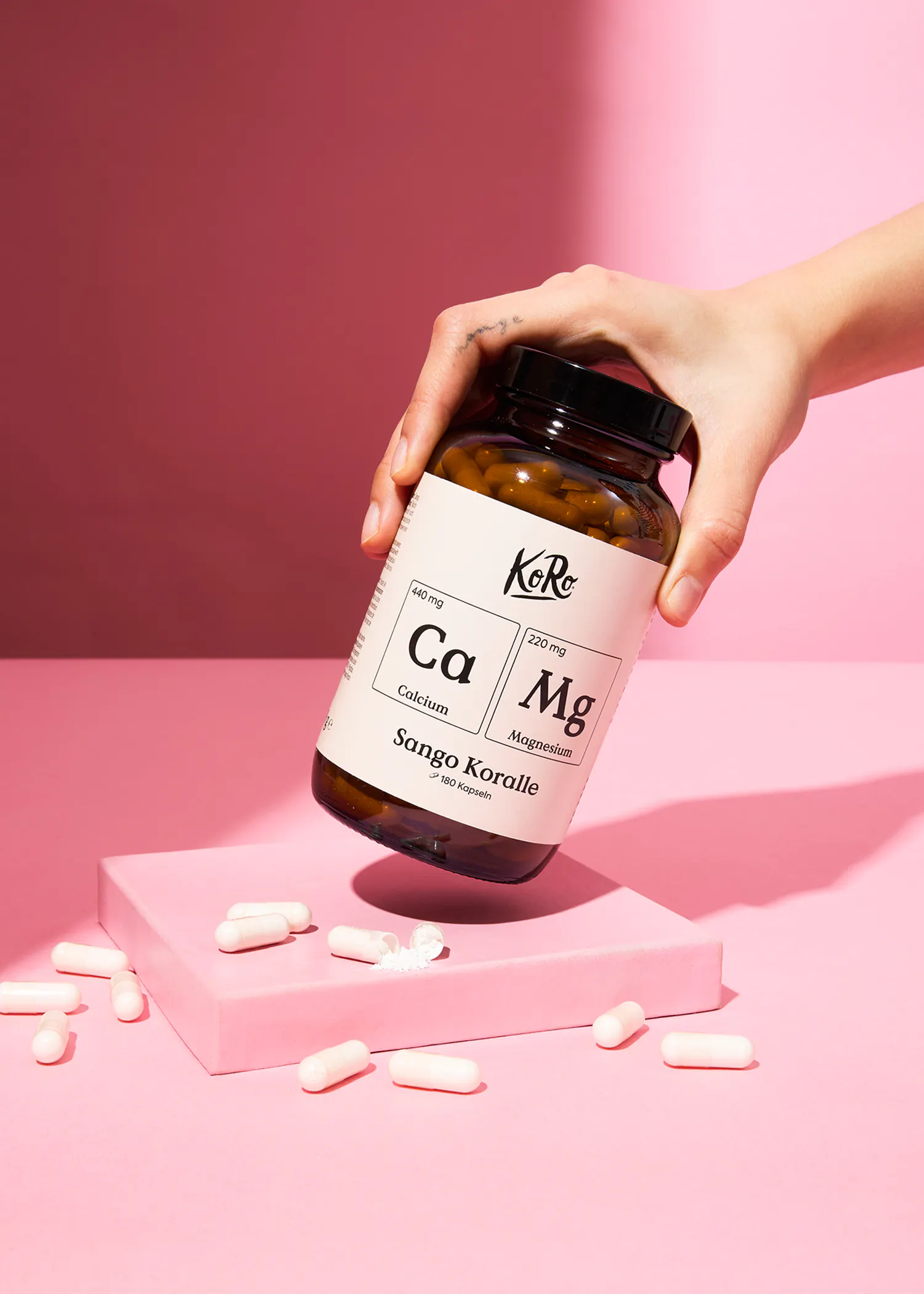 eine hand hält eine flasche mit calcium und magnesium tabletten