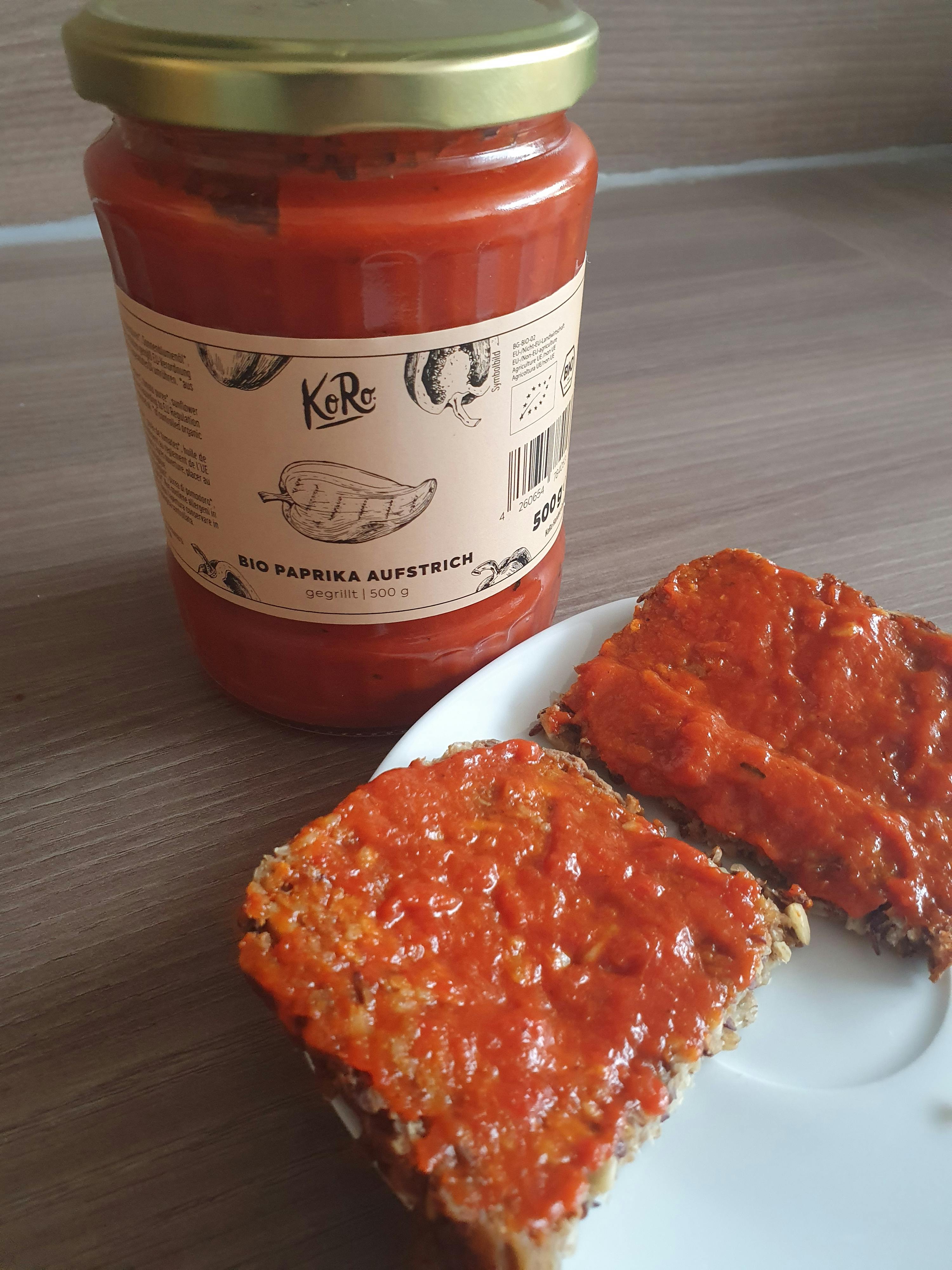 un bocal de paprika bio est posé sur une table à côté d' une tranche de pain