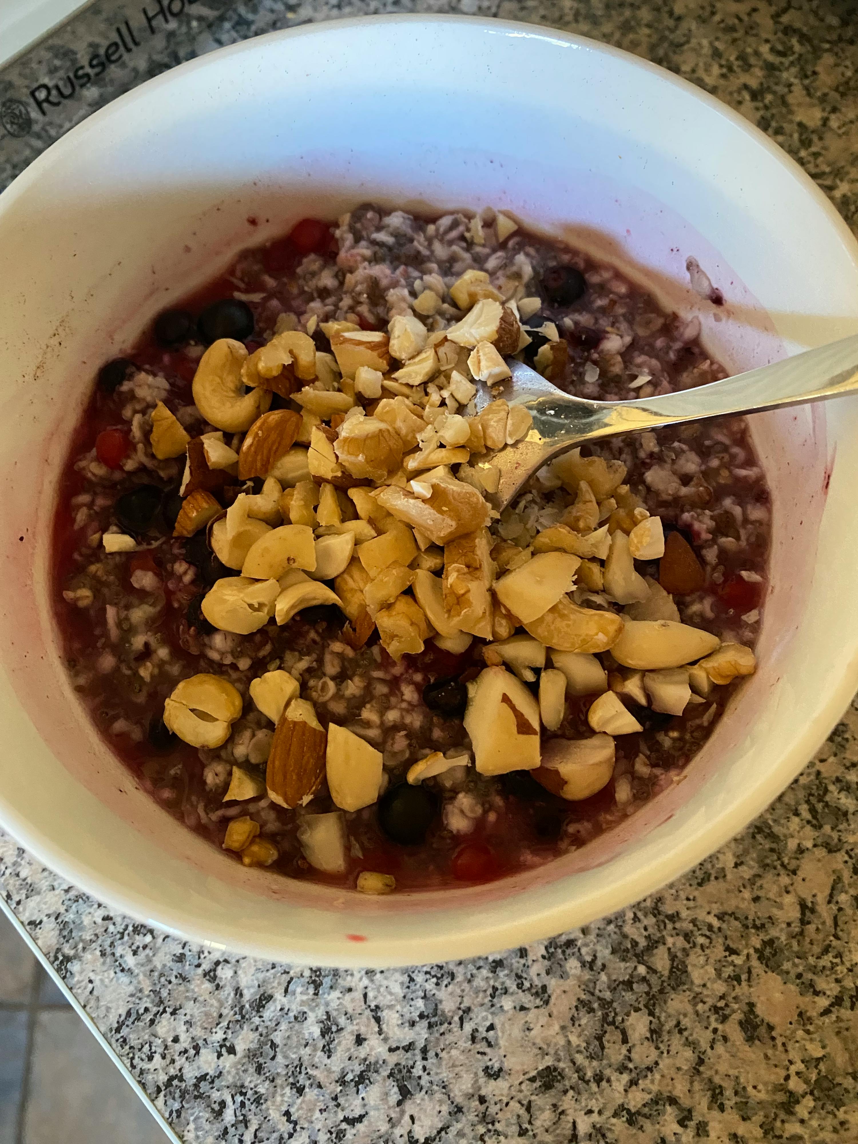 un bol d' avoine avec des baies et des noix est sur une table russell