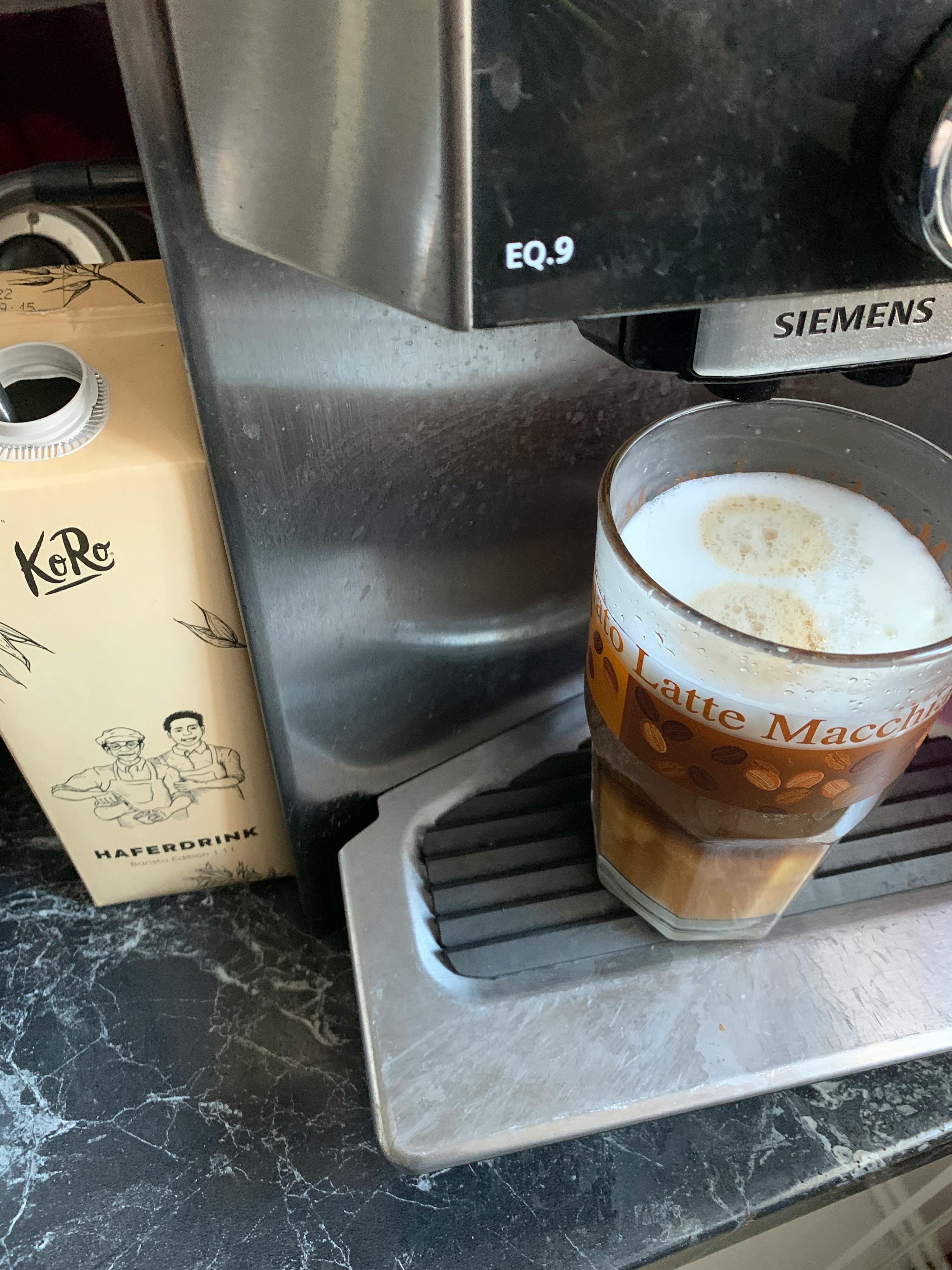 a siemens machine with a glass of latte macchiato next to it