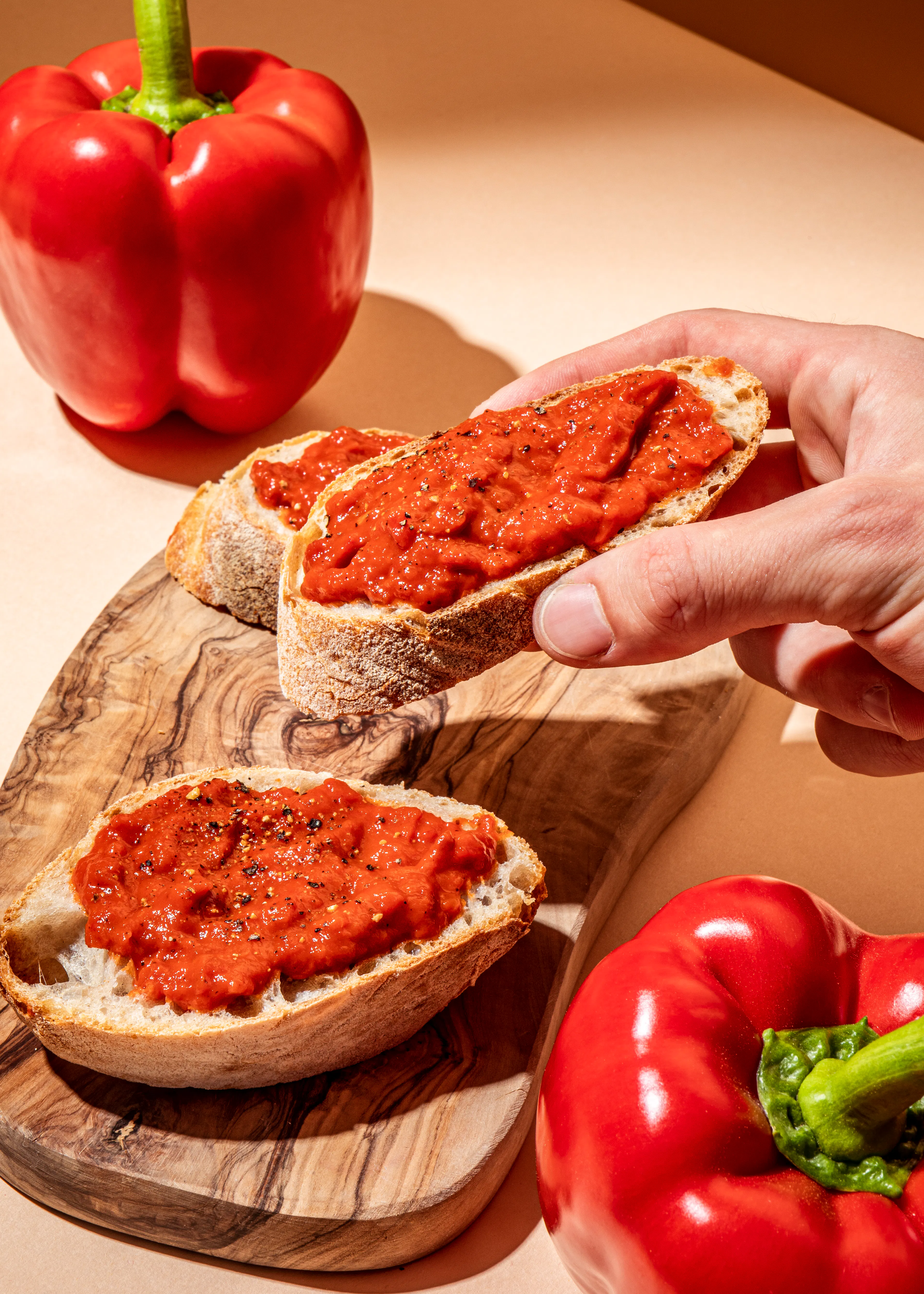 une personne prend une tranche de pain avec de la sauce tomate sur une planche à découper en bois