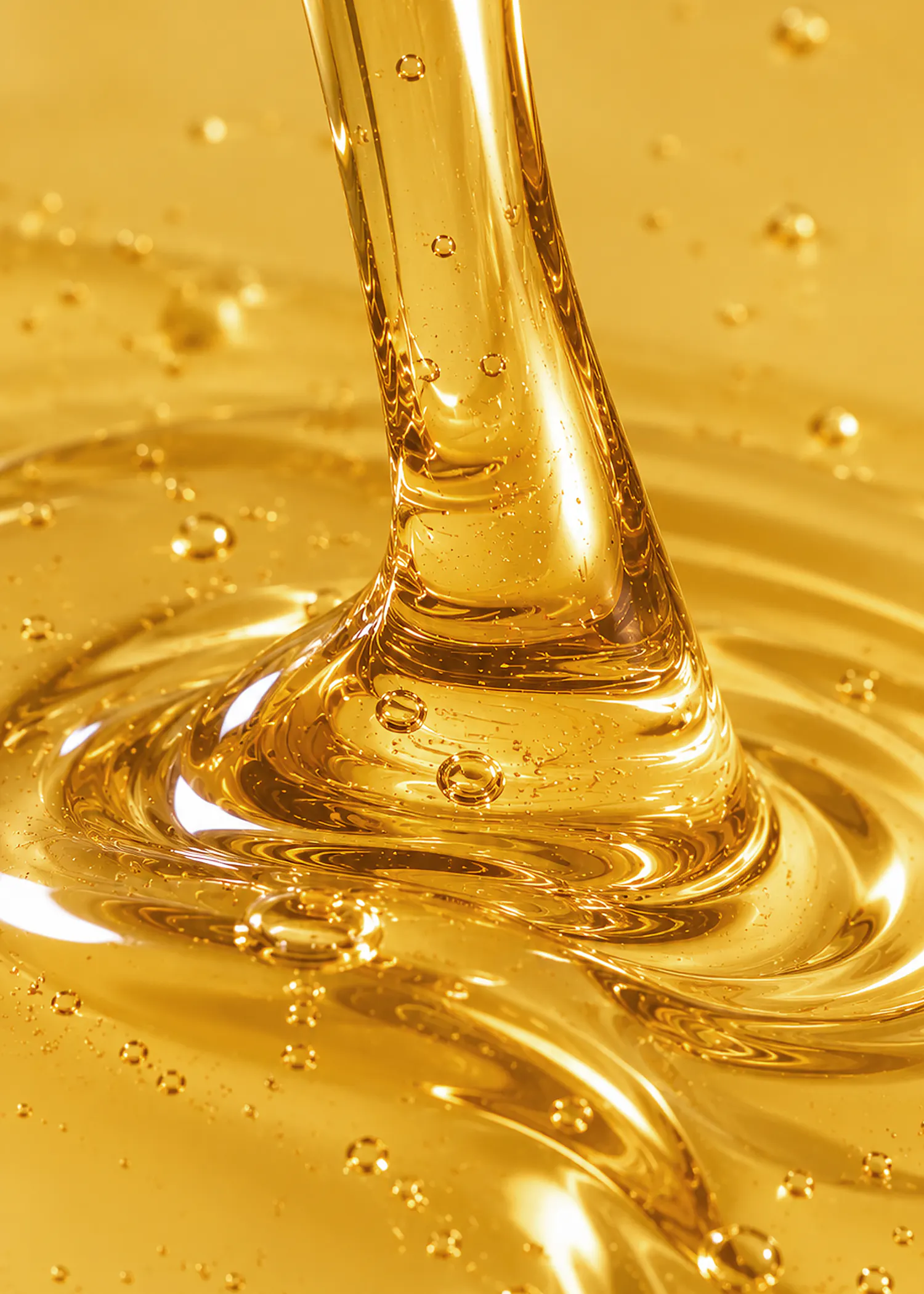 un liquide visqueux et doré coule en formant des ondulations et des bulles à la surface.