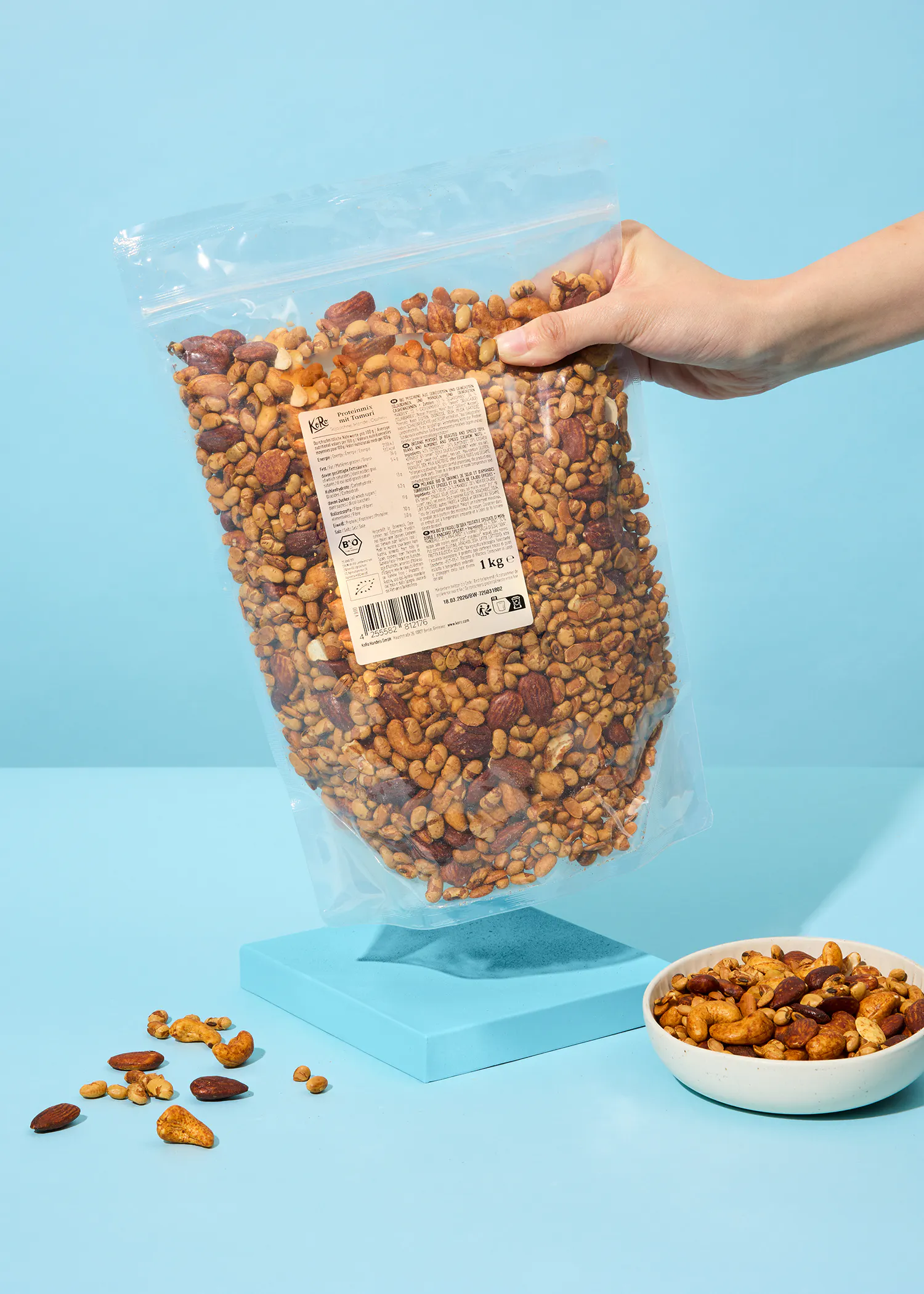 une personne tient un sac de noix sur fond bleu