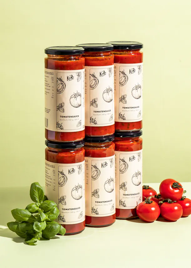 sechs Gläser Tomatensauce stehen nebeneinander auf einem Tisch