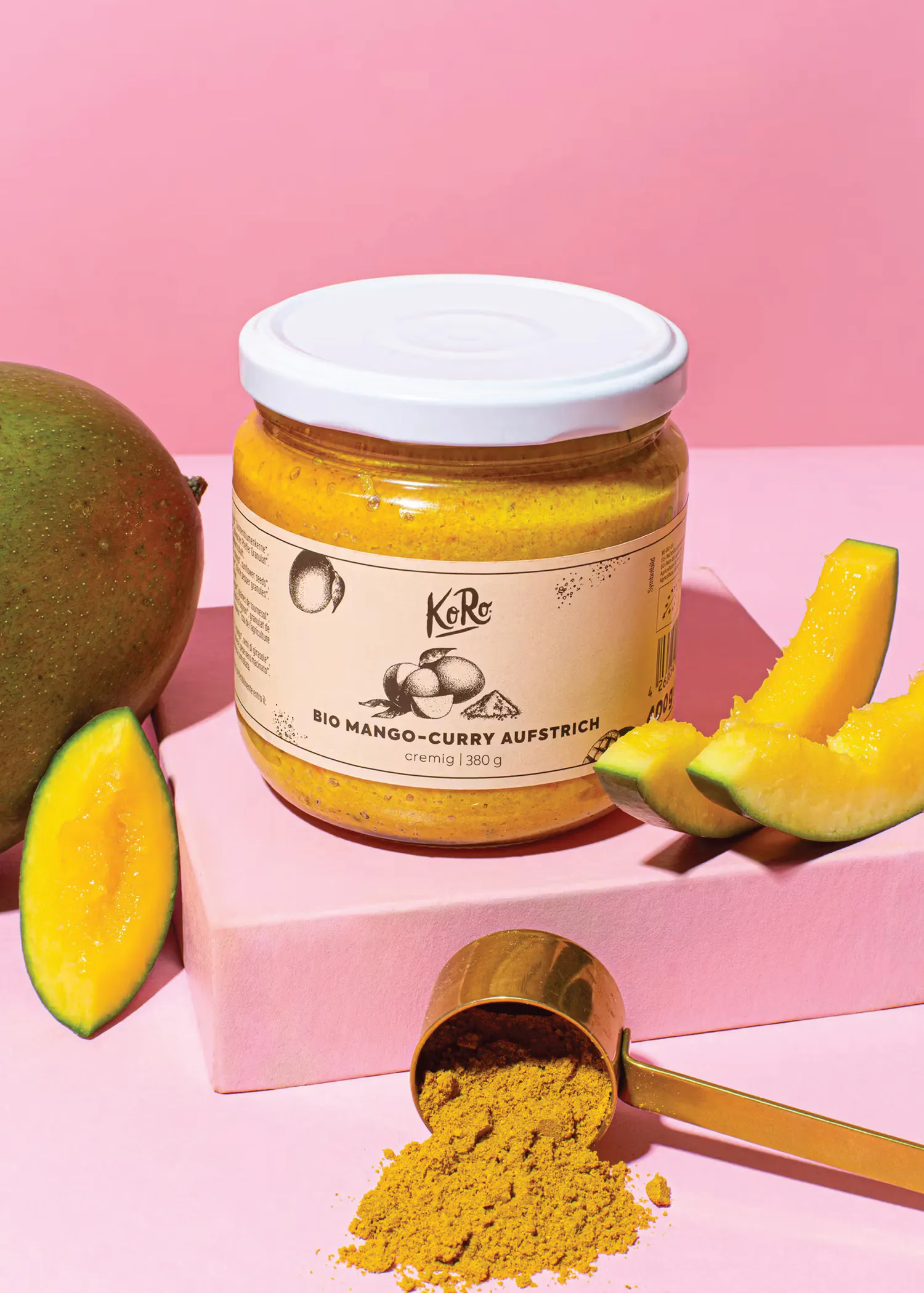 a jar of bio mango-curry aufstrich sits on a pink table