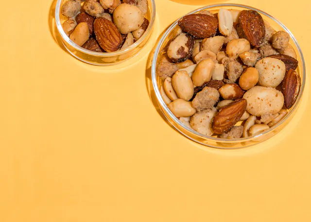 deux bols en verre remplis de noix sur une surface jaune
