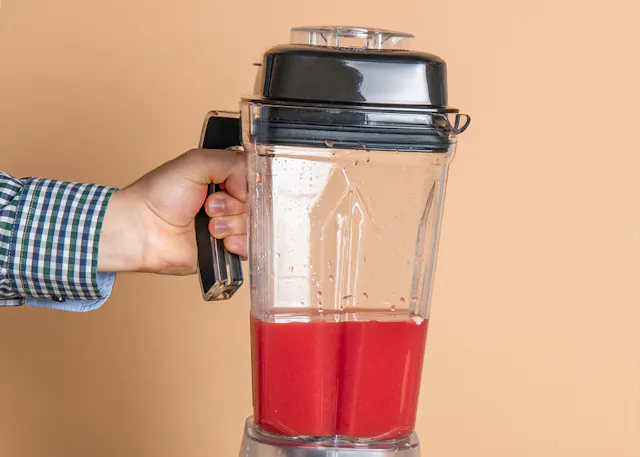 a person is holding a blender full of red liquid