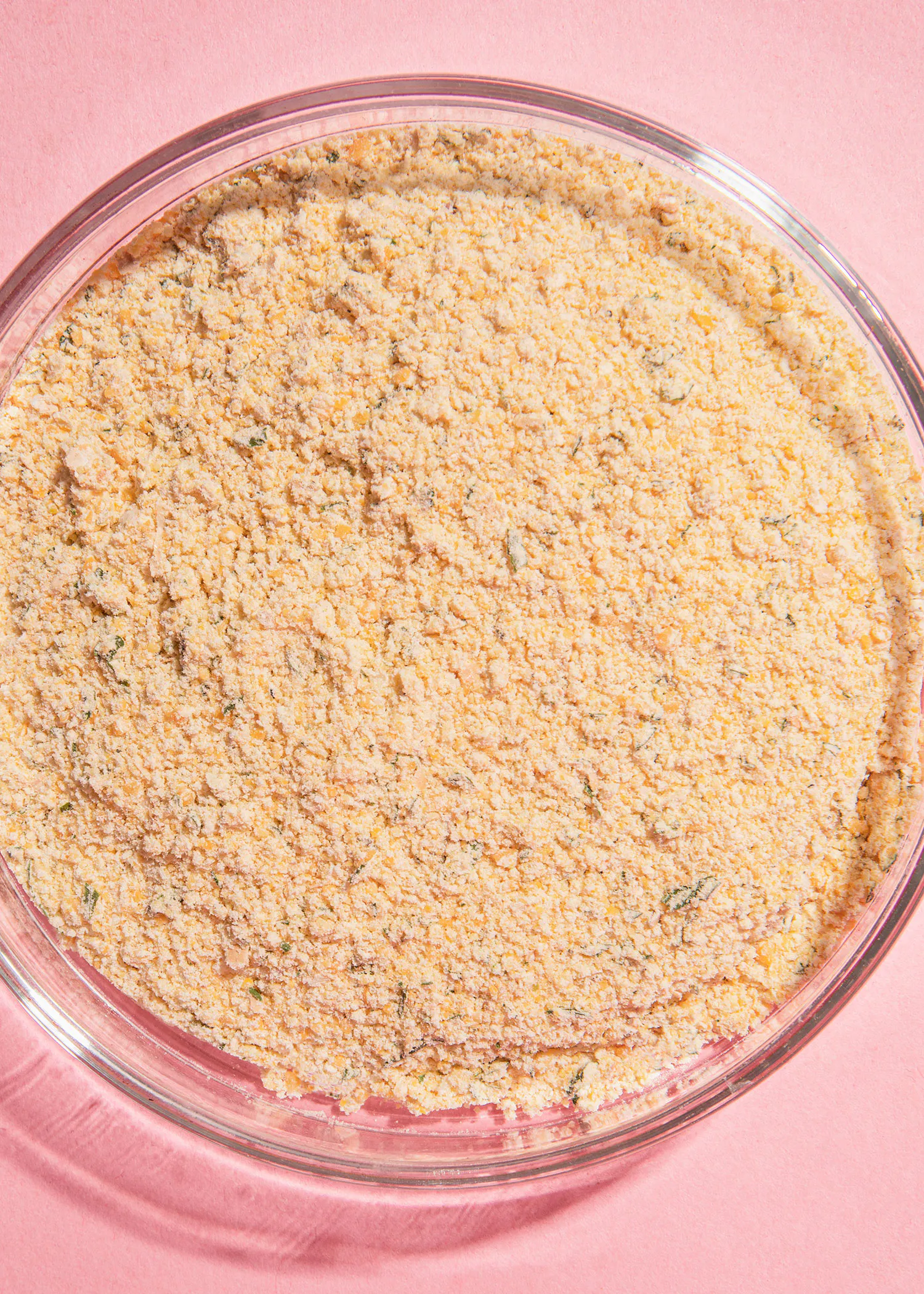 un bol en verre rempli d' un mélange de farine sur une table rose