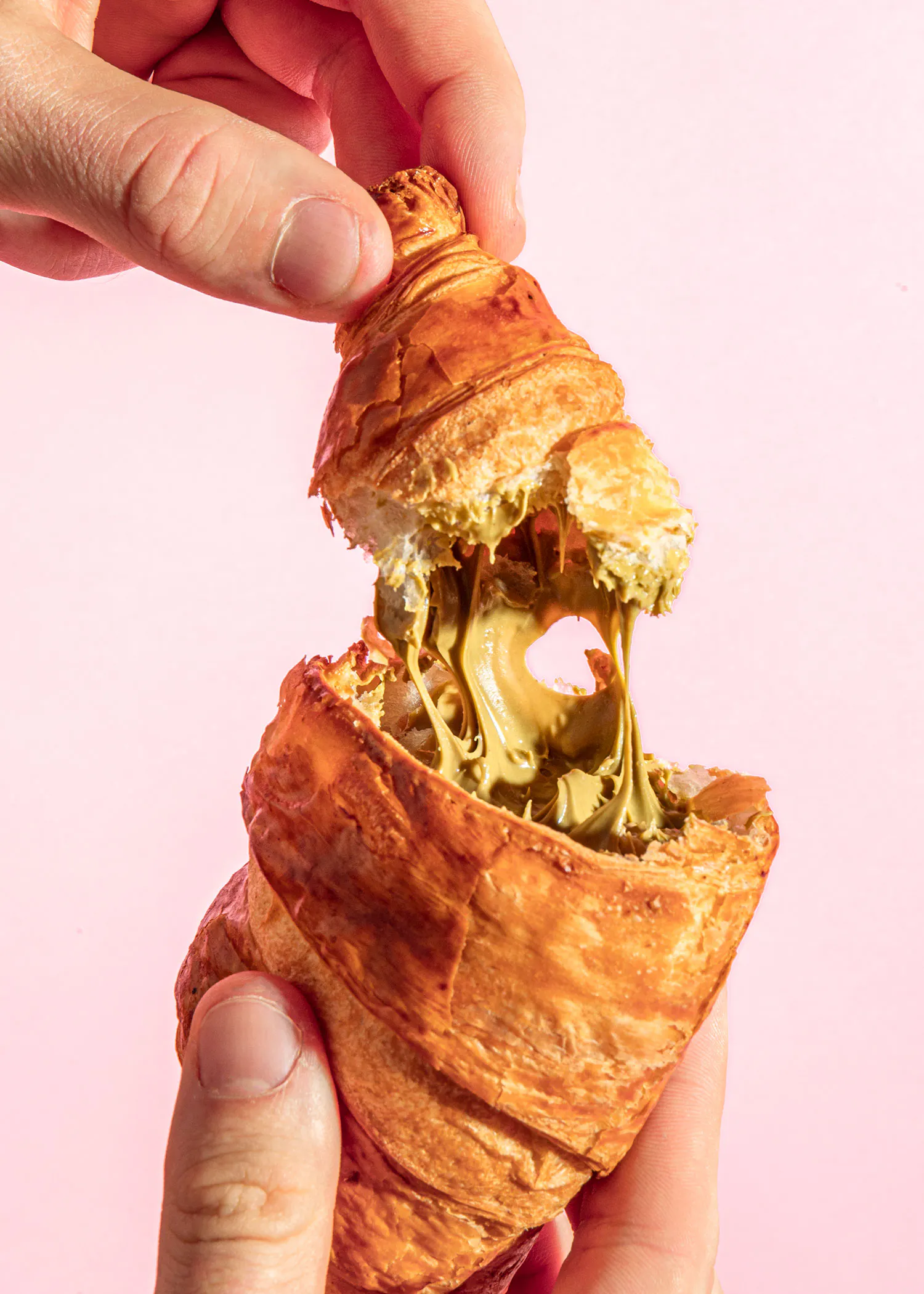 une personne tient un croissant avec du beurre de cacahuète à l' intérieur