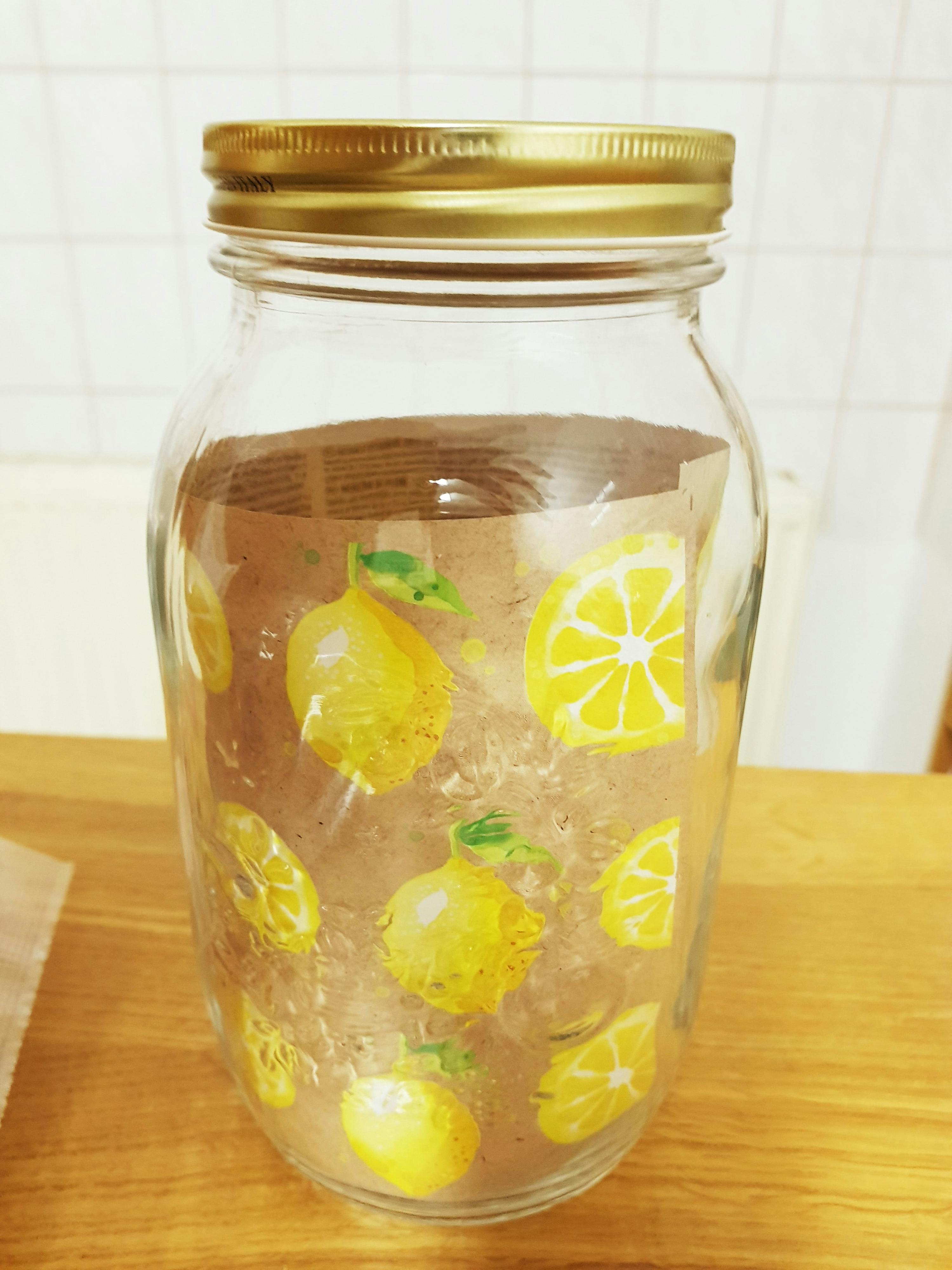 ein Glasgefäß mit einem goldenen Deckel und Zitronenscheiben darauf