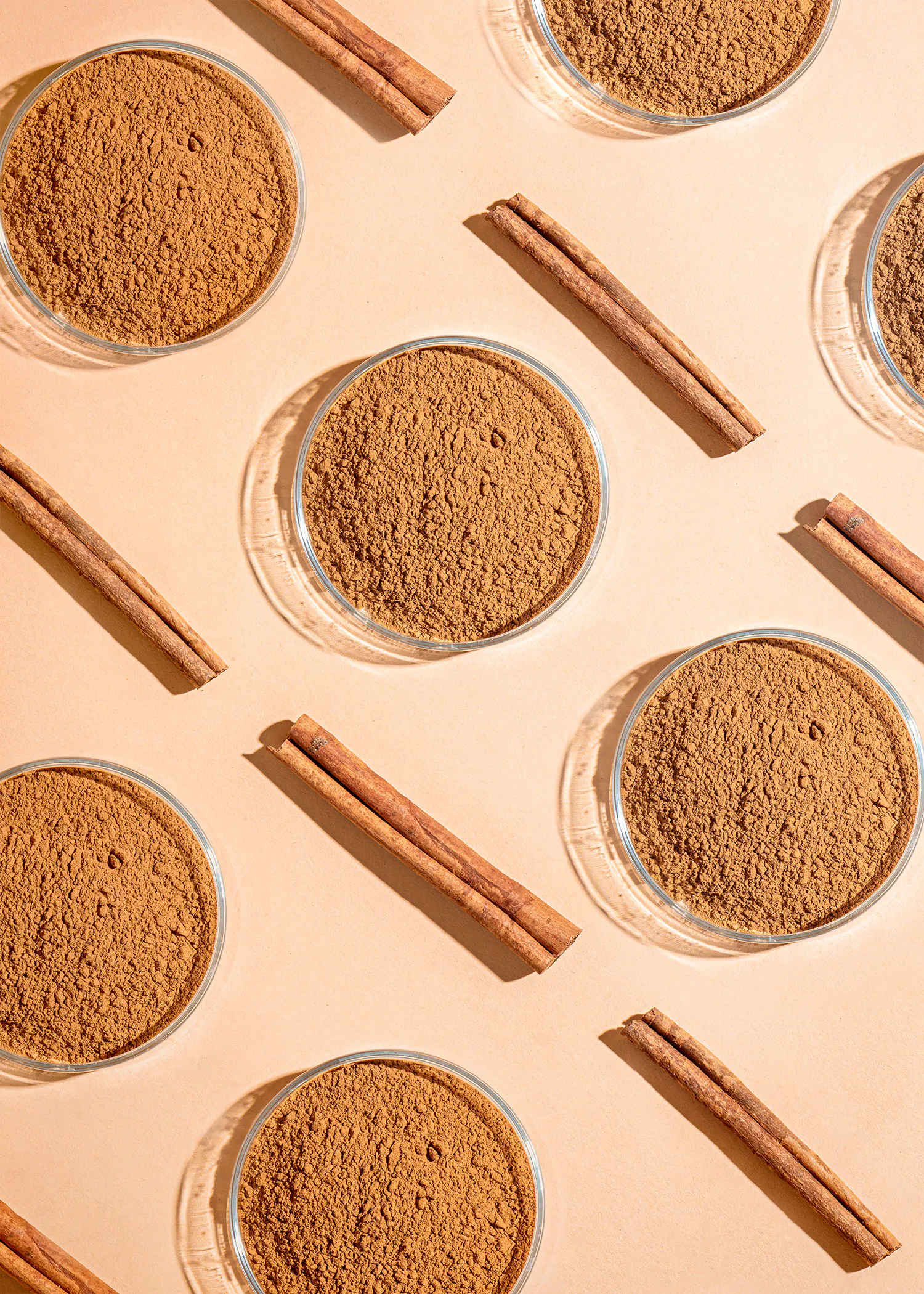quatre bols de poudre de cannelle avec des bâtons de cannelle sur un fond beige