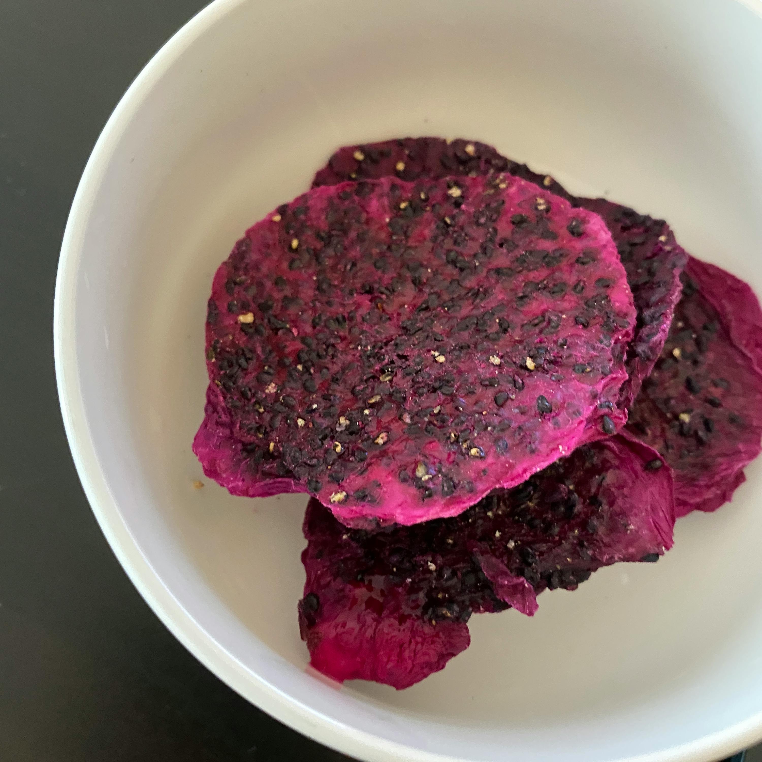 a white bowl filled with purple slices of fruit