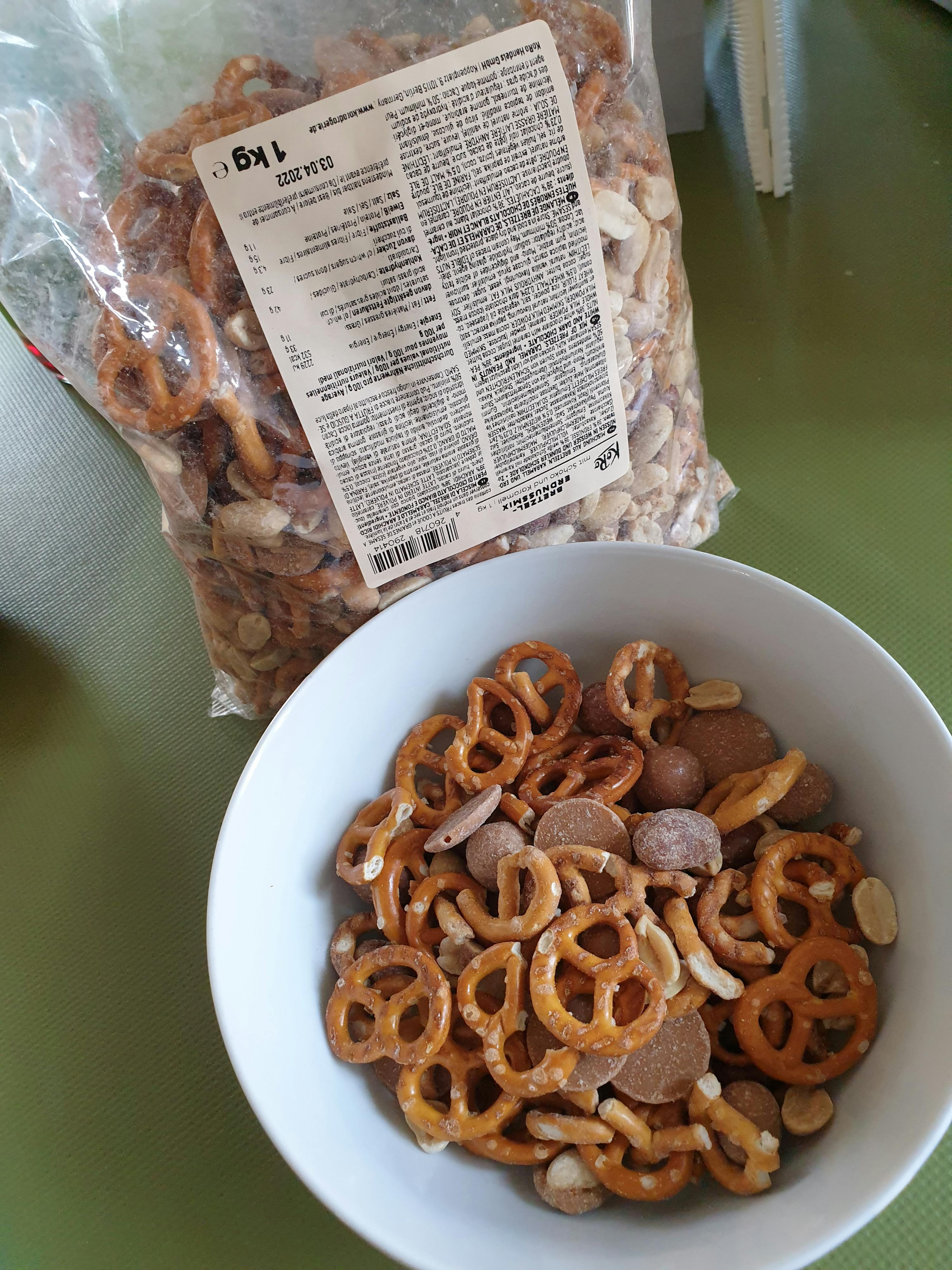 un sac de bretzels est assis à côté d' un bol de bretzels et de noix