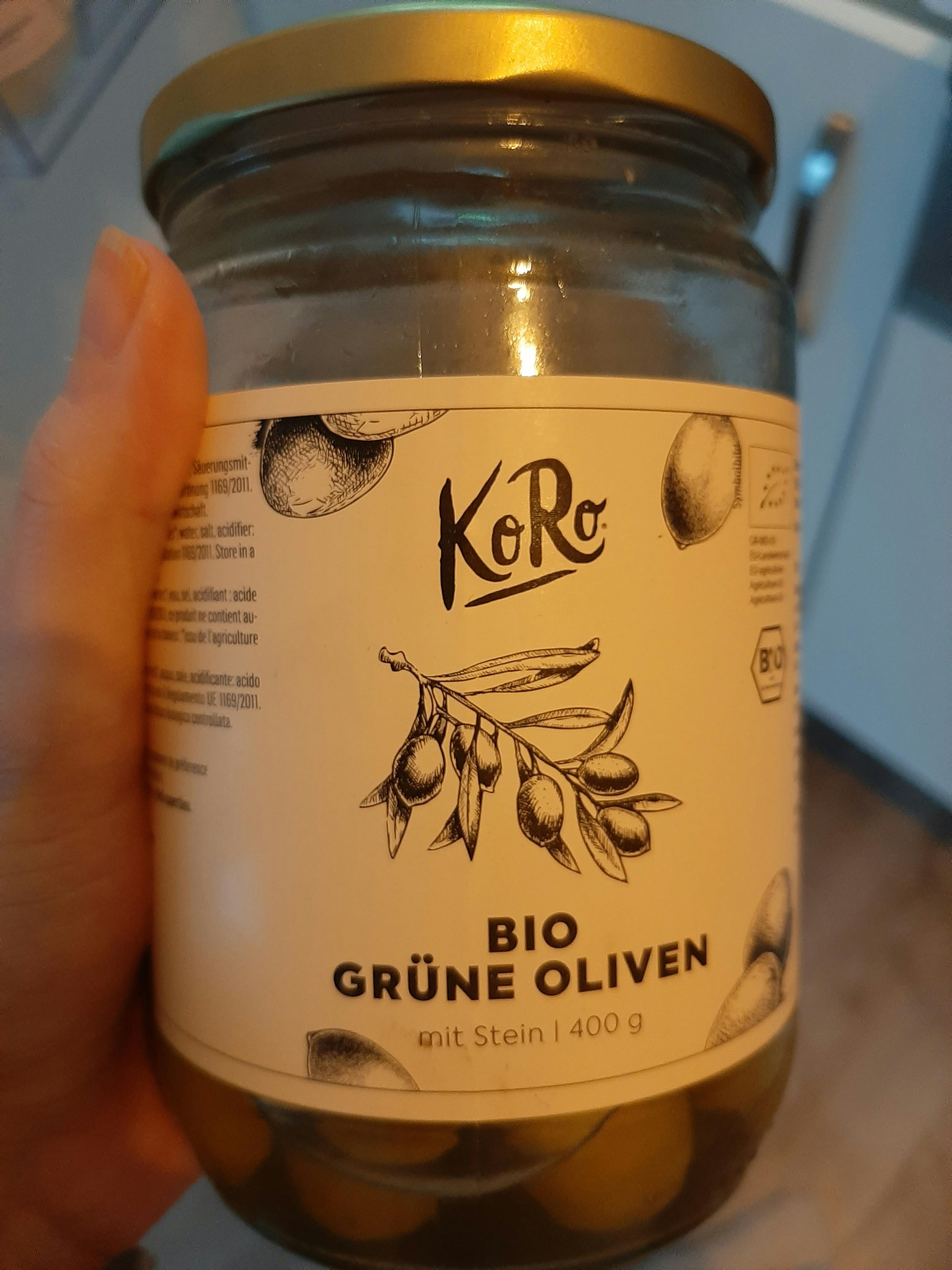 a person is holding a jar of green olives with a label that says " grüne oliven "