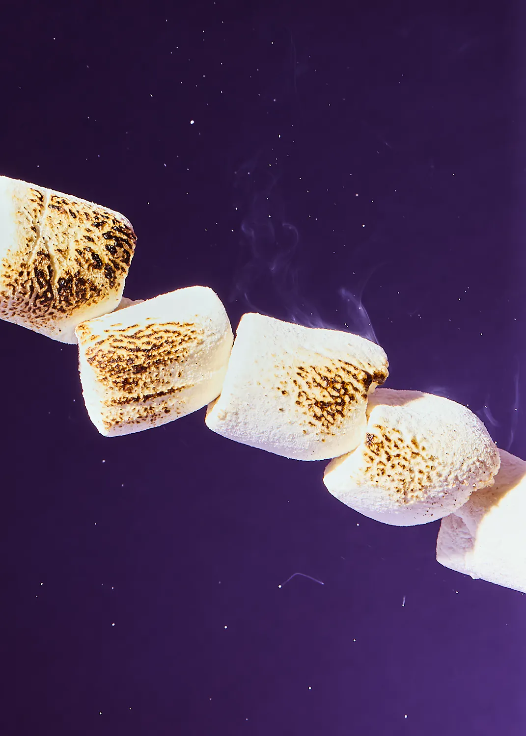 eine Reihe von gegrillten Marshmallows auf einem lila Hintergrund