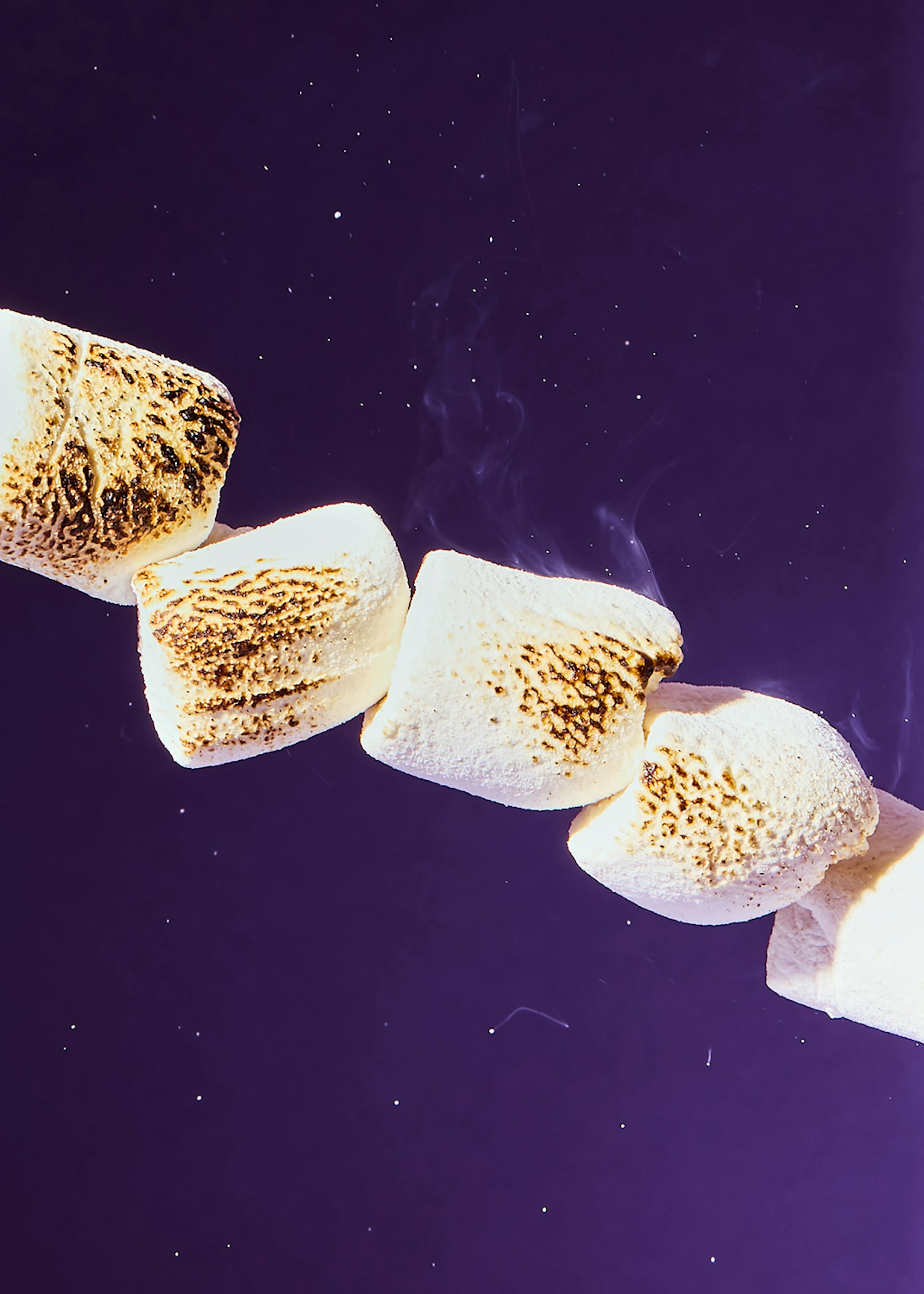 un mucchio di marshmallow cotti e fumanti su sfondo viola