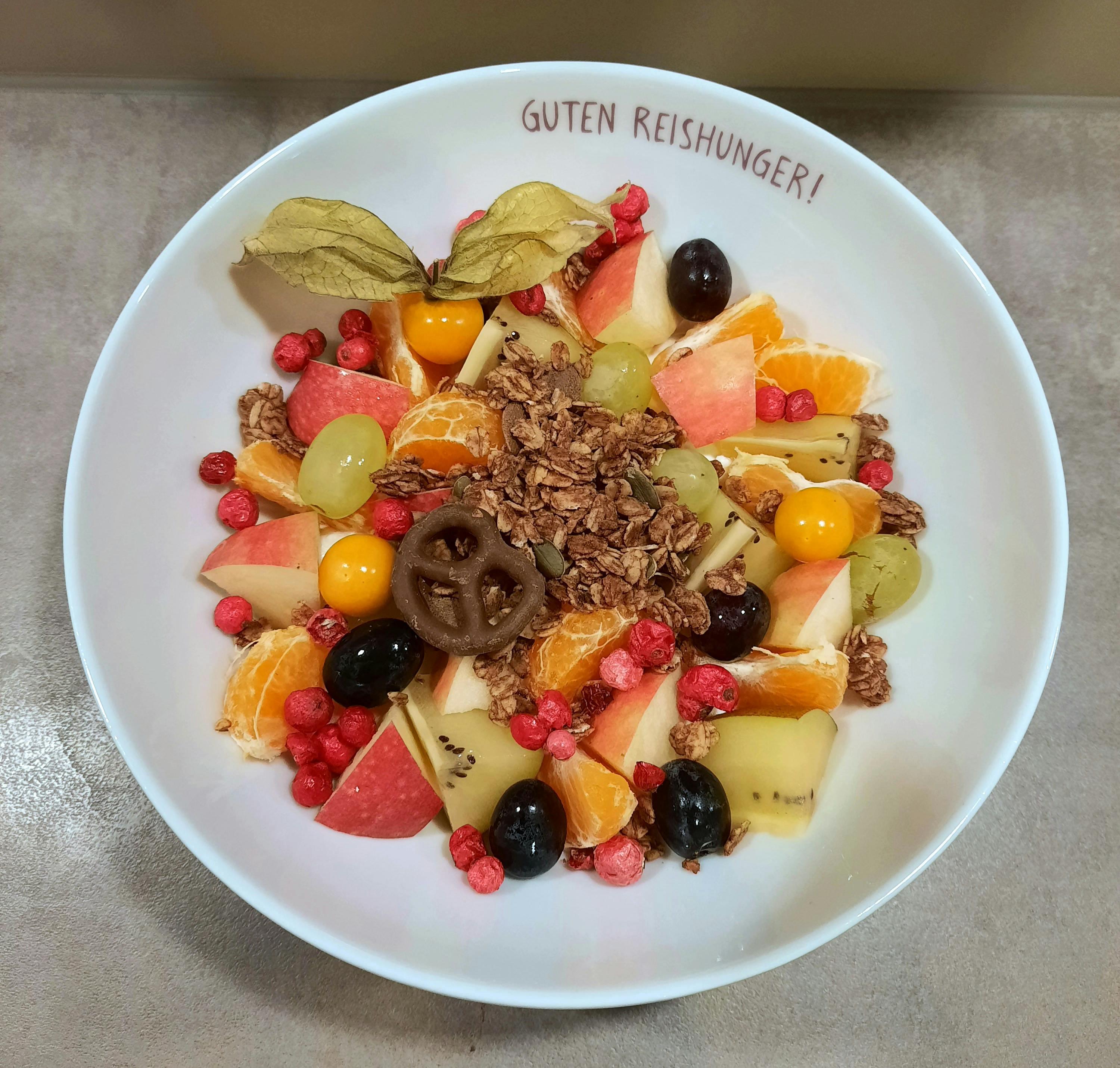 a bowl of fruit and granola with the words guten reishunger written on it