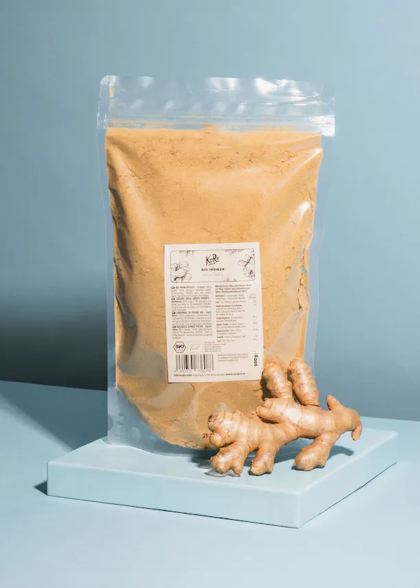 un sac de poudre de gingembre est assis à côté d' une racine de gingembre