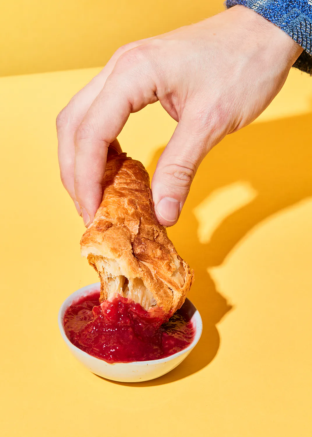 eine Person nimmt einen Stück Brot mit Marmelade aus einer Schüssel