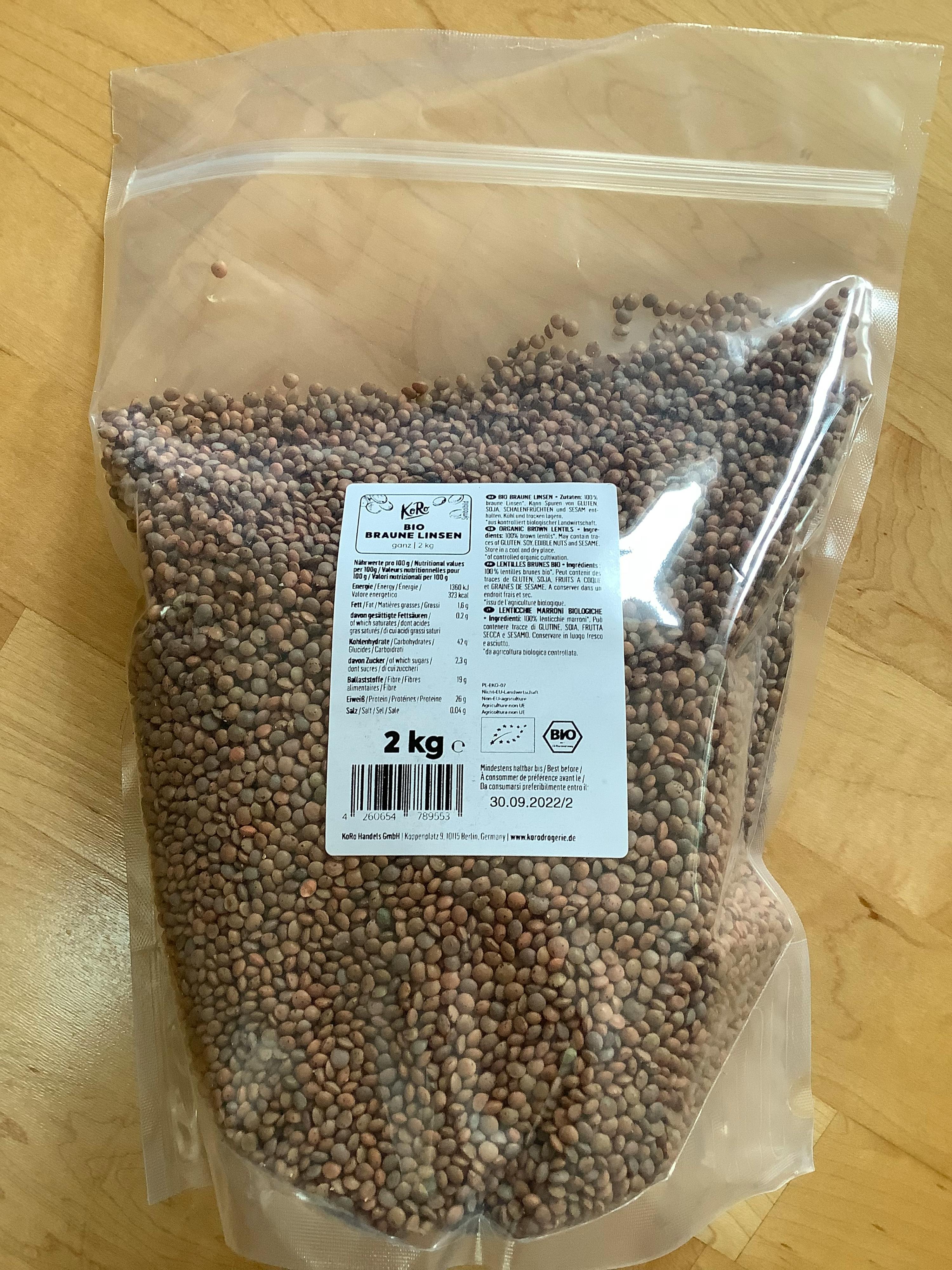 un sac de lentilles brunes avec une étiquette de 2 kg sur une table en bois