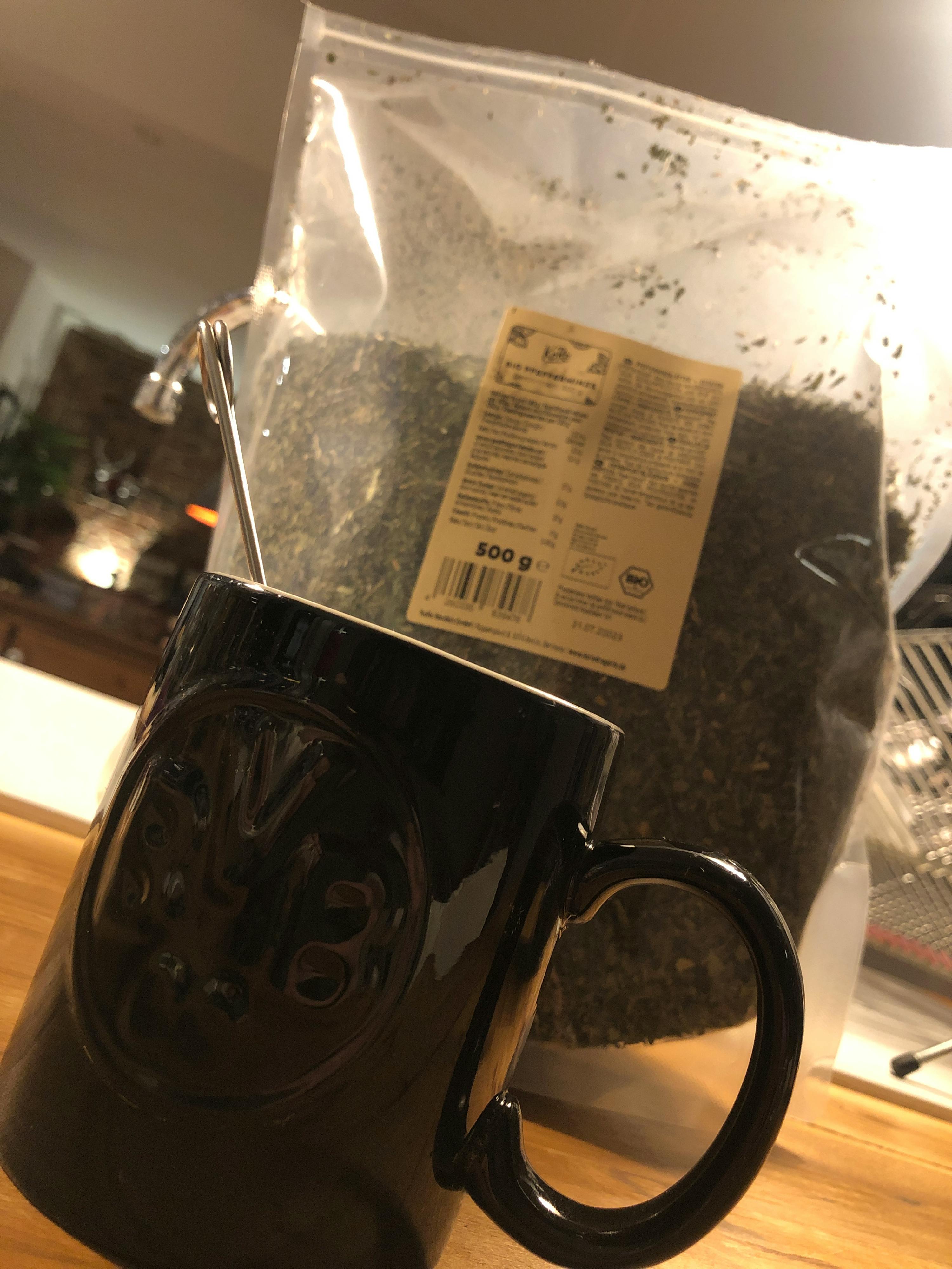 eine schwarze tasse steht neben einem beutel tee