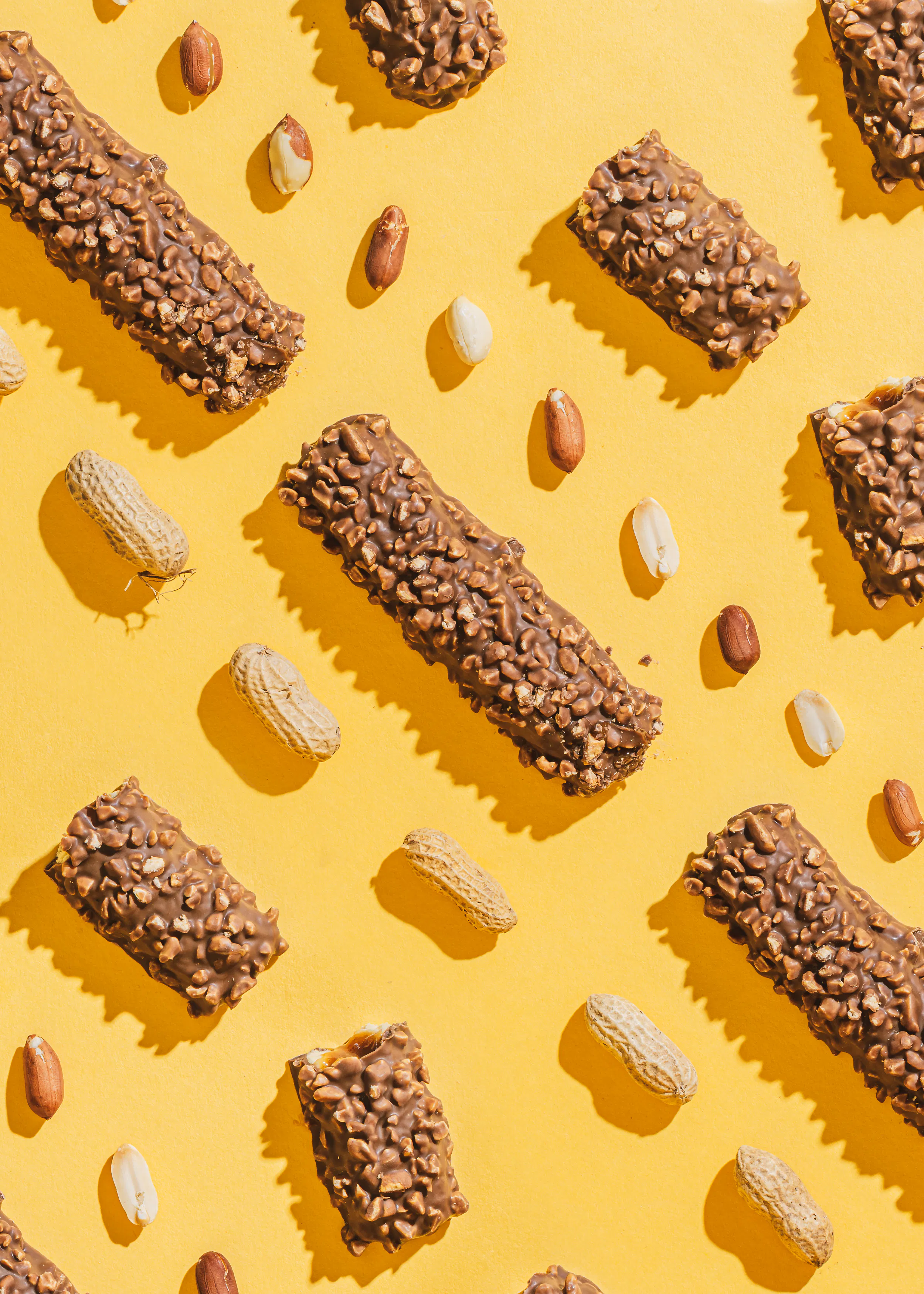 a pattern of chocolate bars and peanuts on a yellow surface