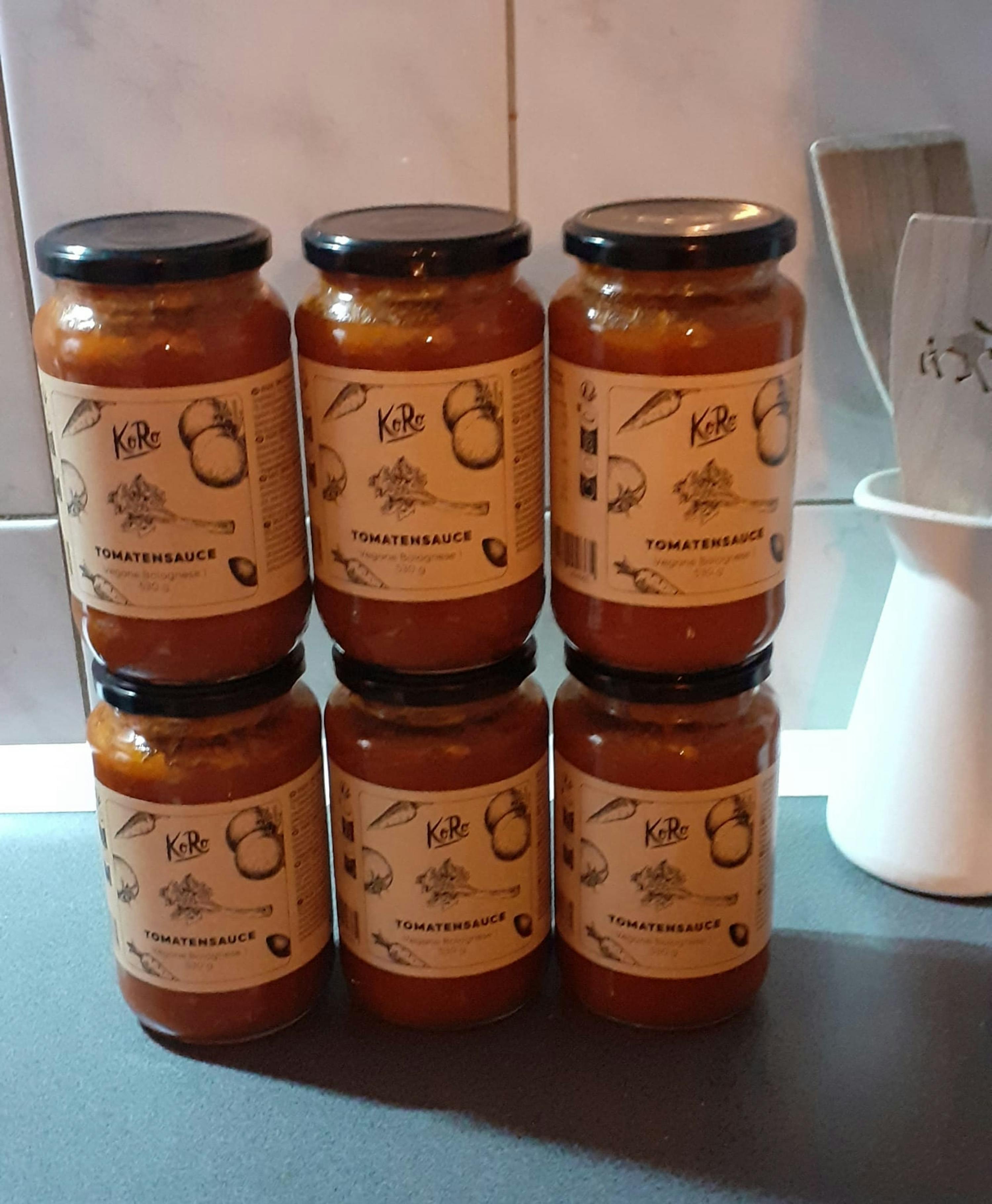 quattro barattoli di salsa di pomodoro sono impilati uno sopra l' altro