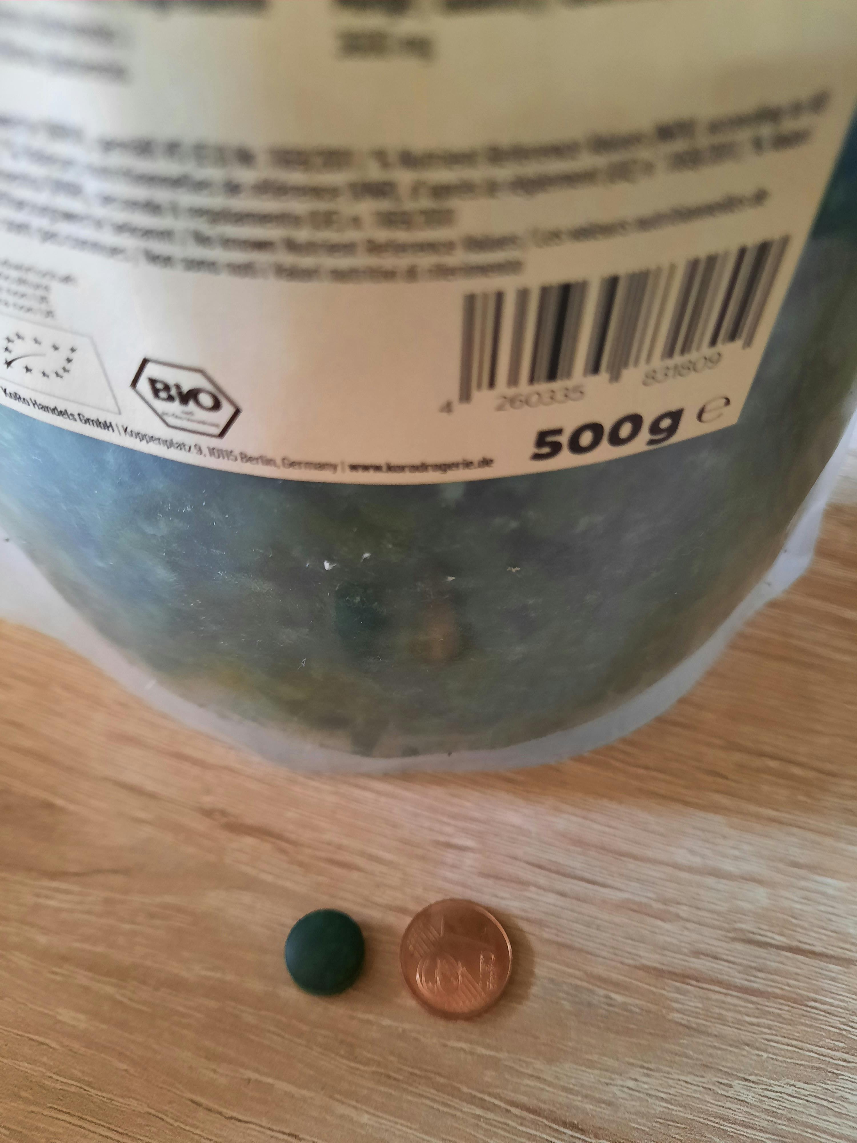 a 500g container of food sits on a table next to a penny
