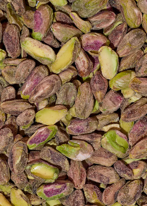 nahaufnahme von vielen geschälten pistazien mit grünen und violetten kernen.