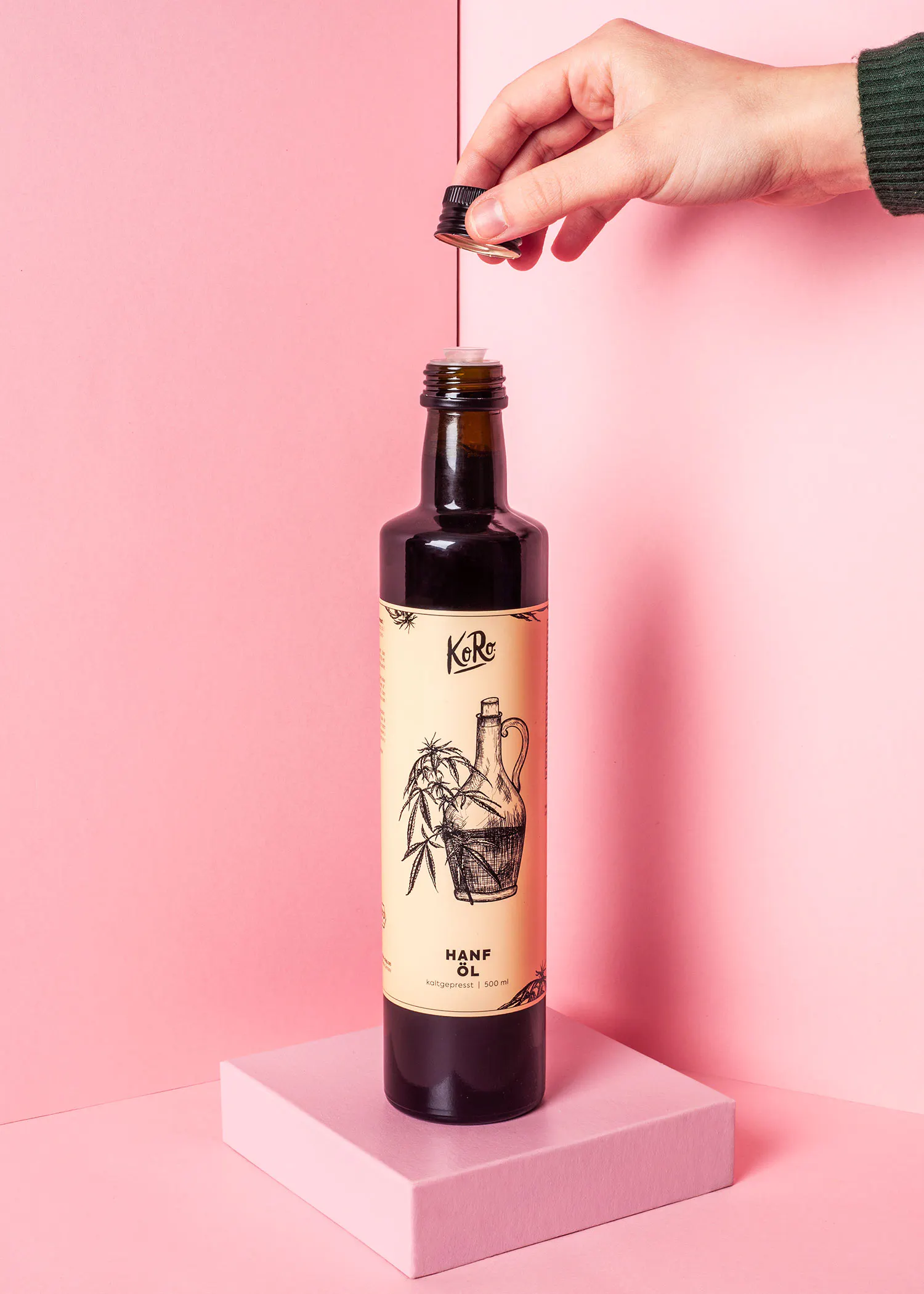 eine hand gießt hanföl aus einer flasche